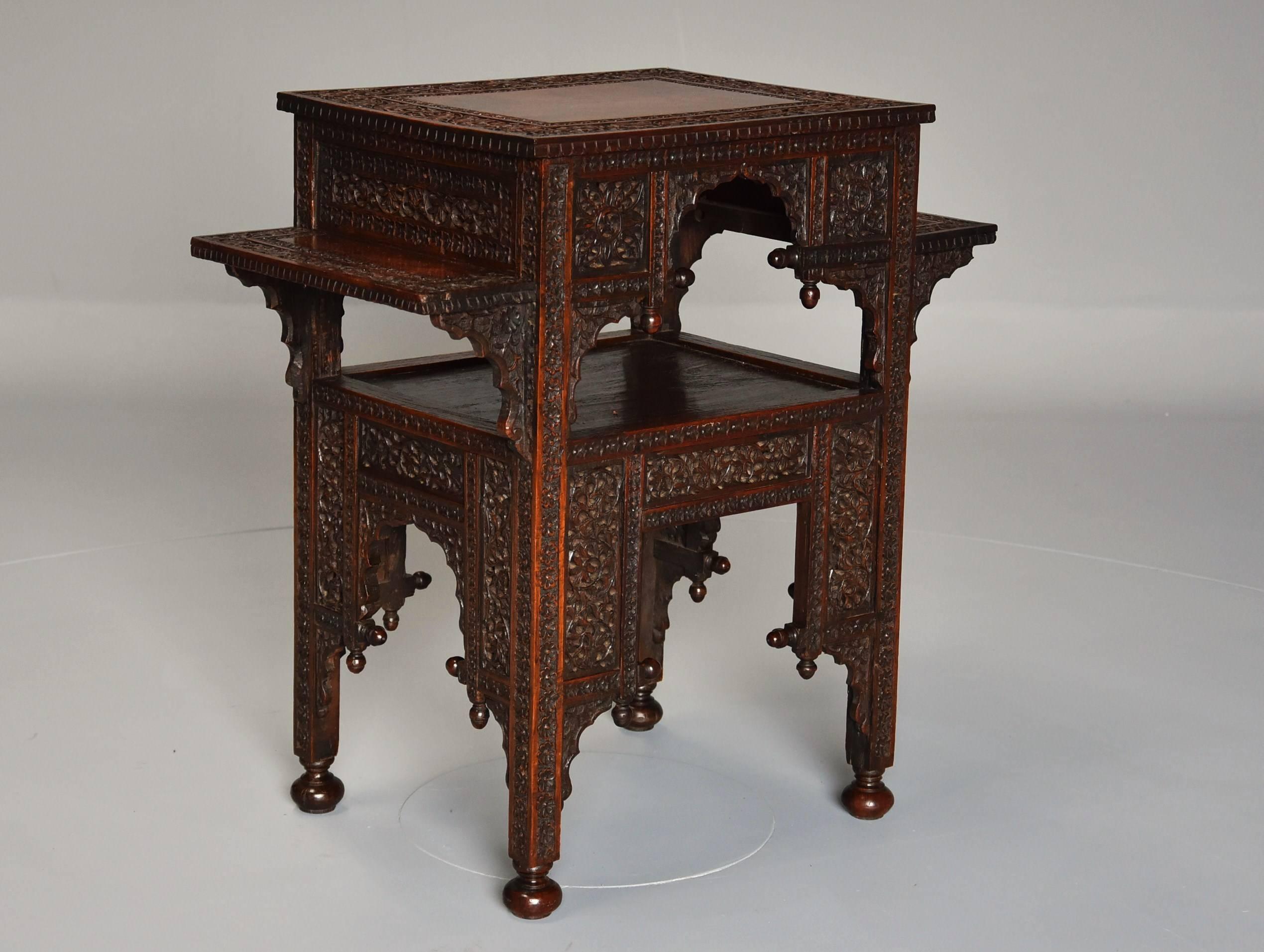 A late 19th century Anglo-Indian padouk two-tier freestanding occasional table.

This table consists of a rectangular top with carved floral border leading onto a wider frieze profusely carved with foliate decoration.

This leads down to a