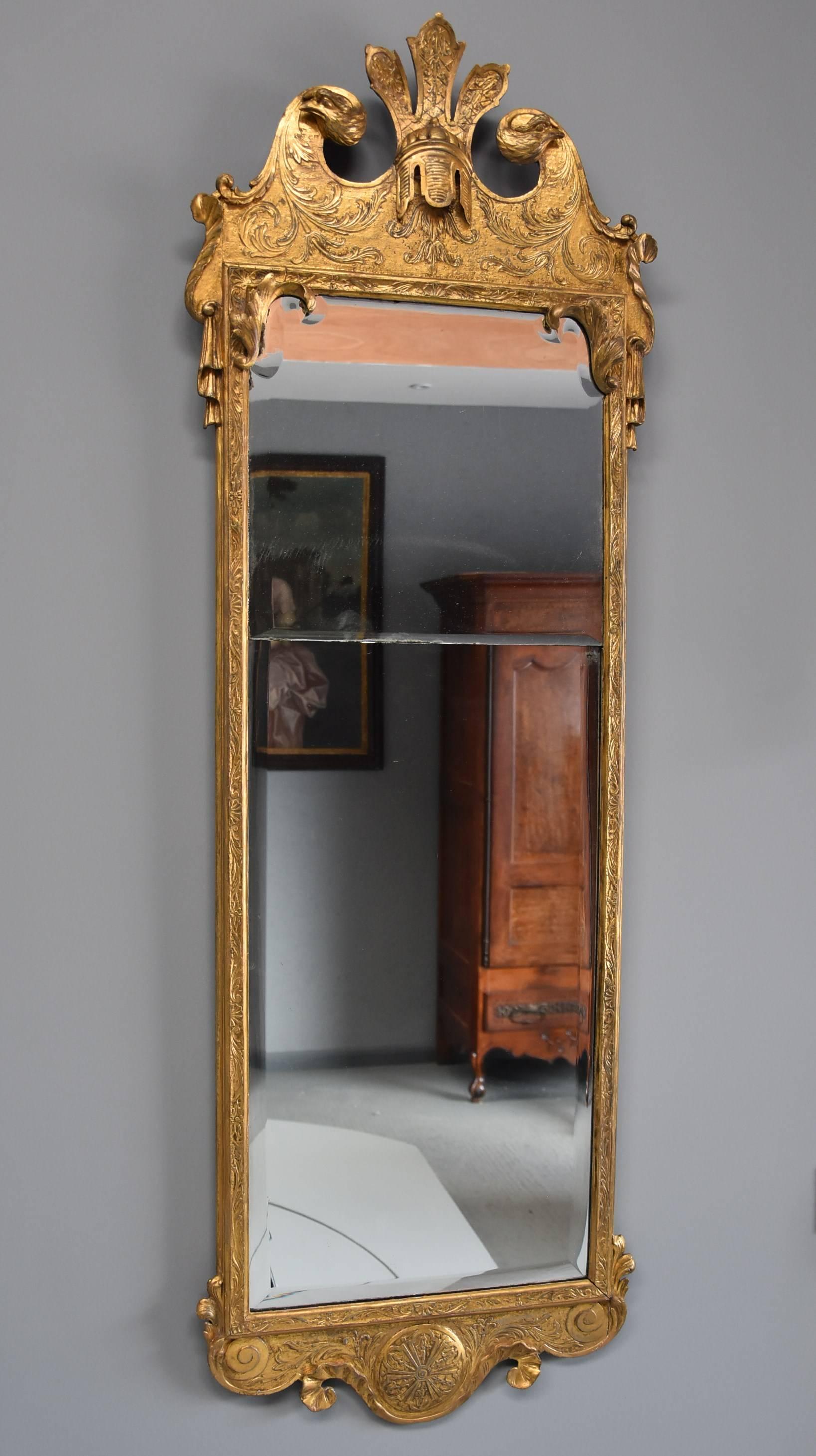 A large early 18th century rare George I giltwood and gesso pier mirror retaining both original gilding and plate, in the manner of John Belchier.

The carved wood and gesso mirror frame retains the original gilding and consists of a broken scroll