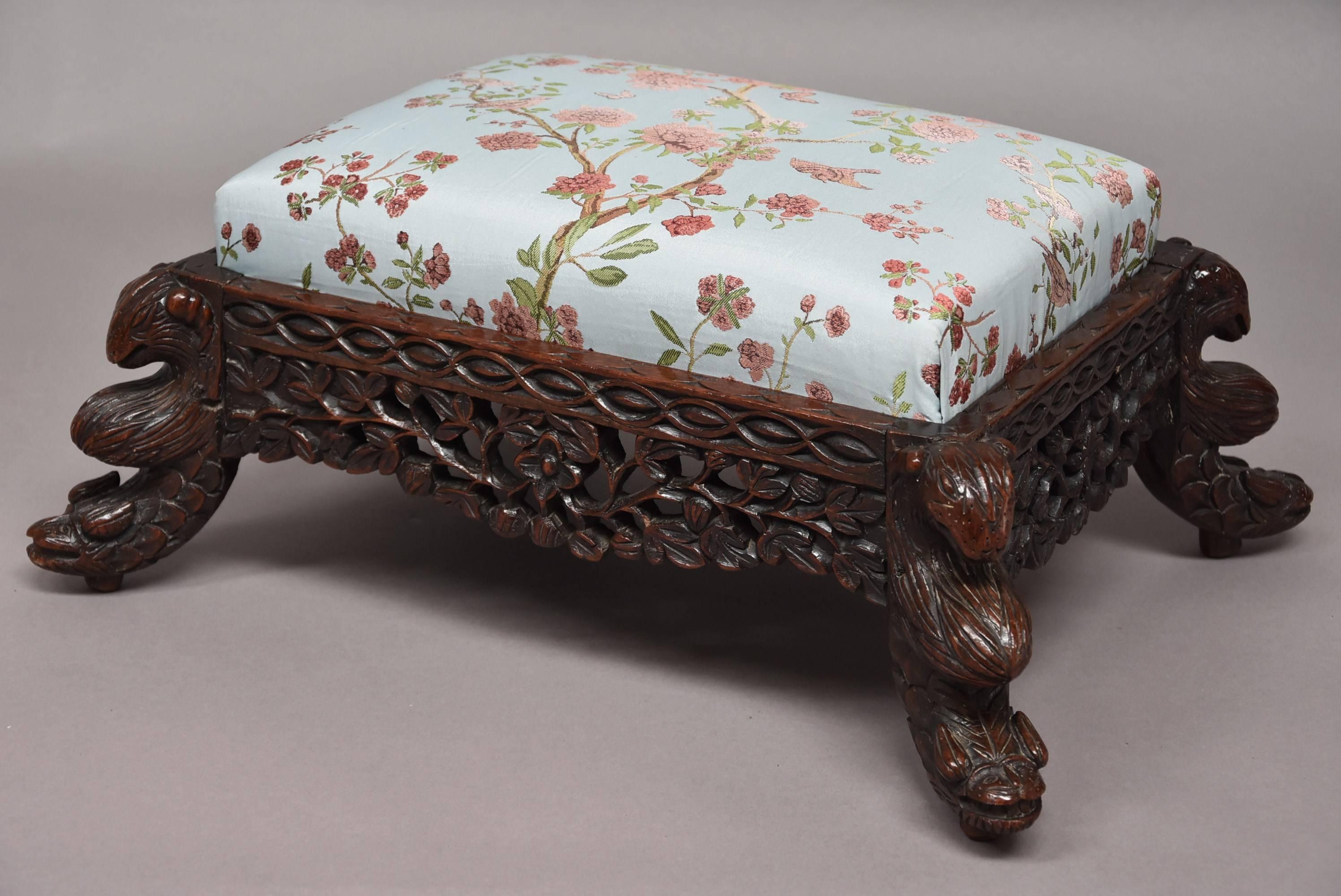 A decorative late 19th century hardwood Anglo-Indian footstool.

This stool consists of a drop in cushion to the top covered in a silk fabric (this can easily be reupholstered if necessary once purchased).

The stool consists of a mythical