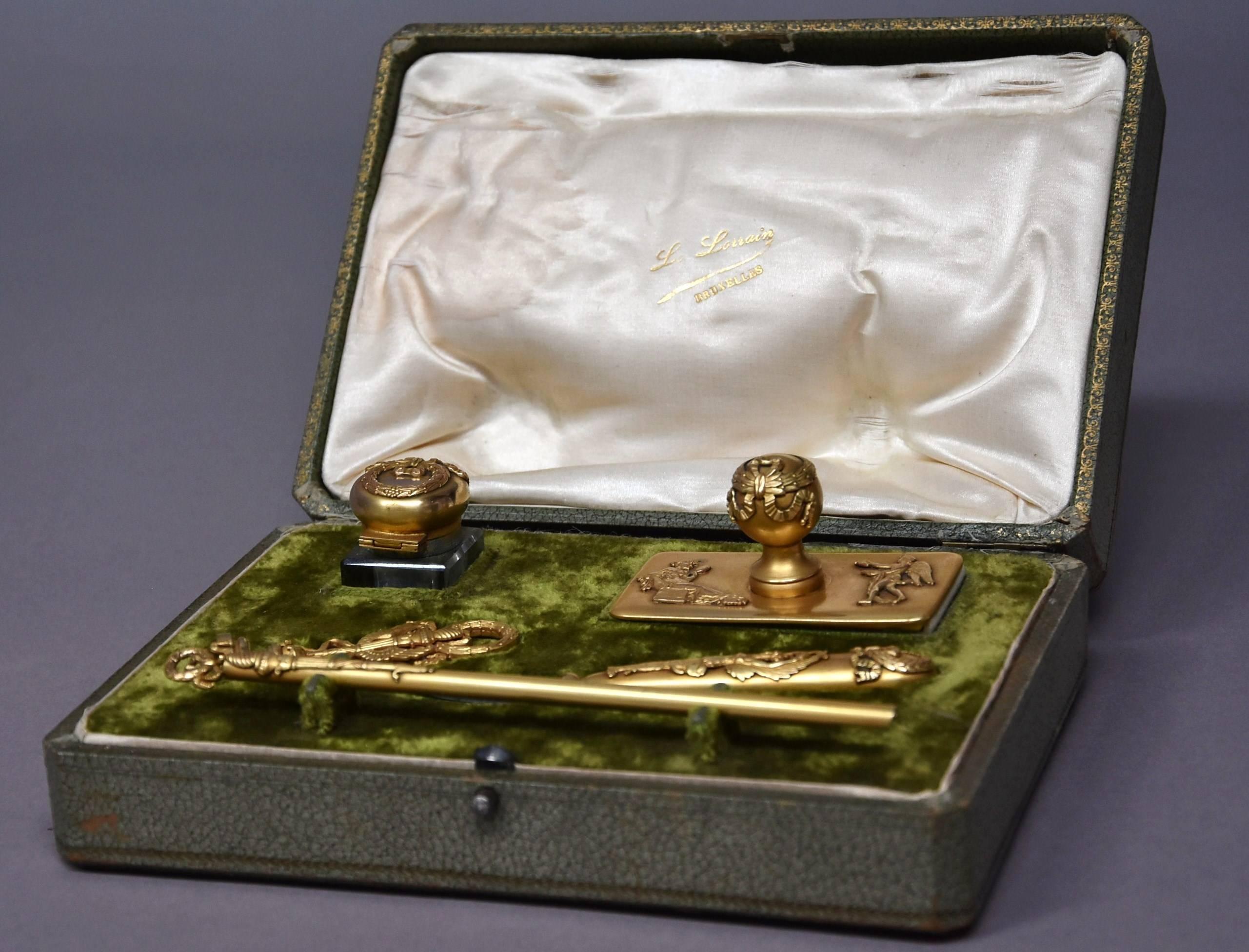 An exceptional quality early 20th century five-piece gilt metal writing set in the Empire style and in original case.

This highly decorative set consists of a glass inkwell, blotter, wax seal, letter opener and pen all with gilt metal Empire