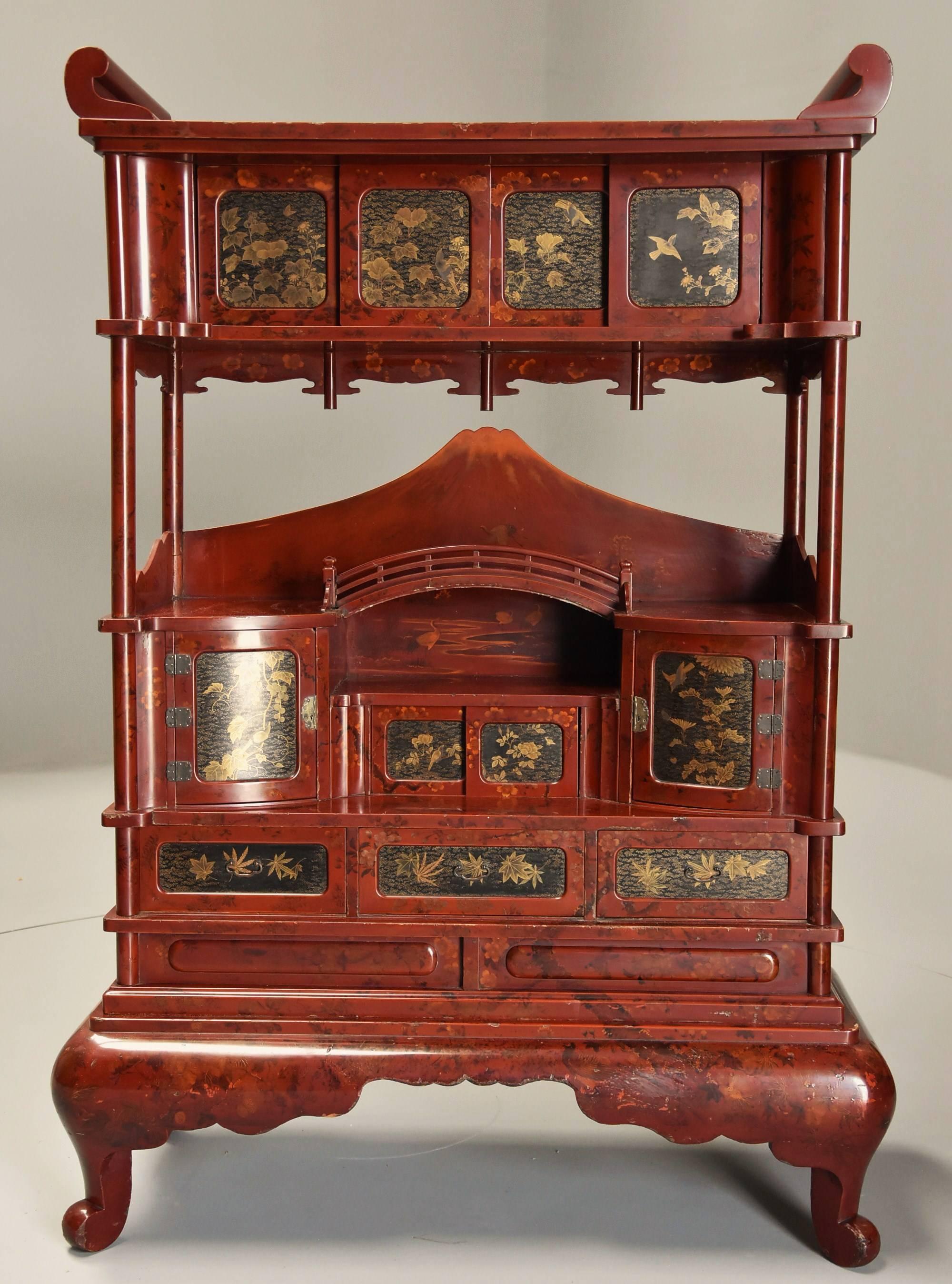 An early 20th century Japanese red lacquered decorative freestanding shodana (cabinet).

The body of this shodana is finished in a red lacquer with tree, flower, foliate and bird decoration to the front, sides and back making this a freestanding