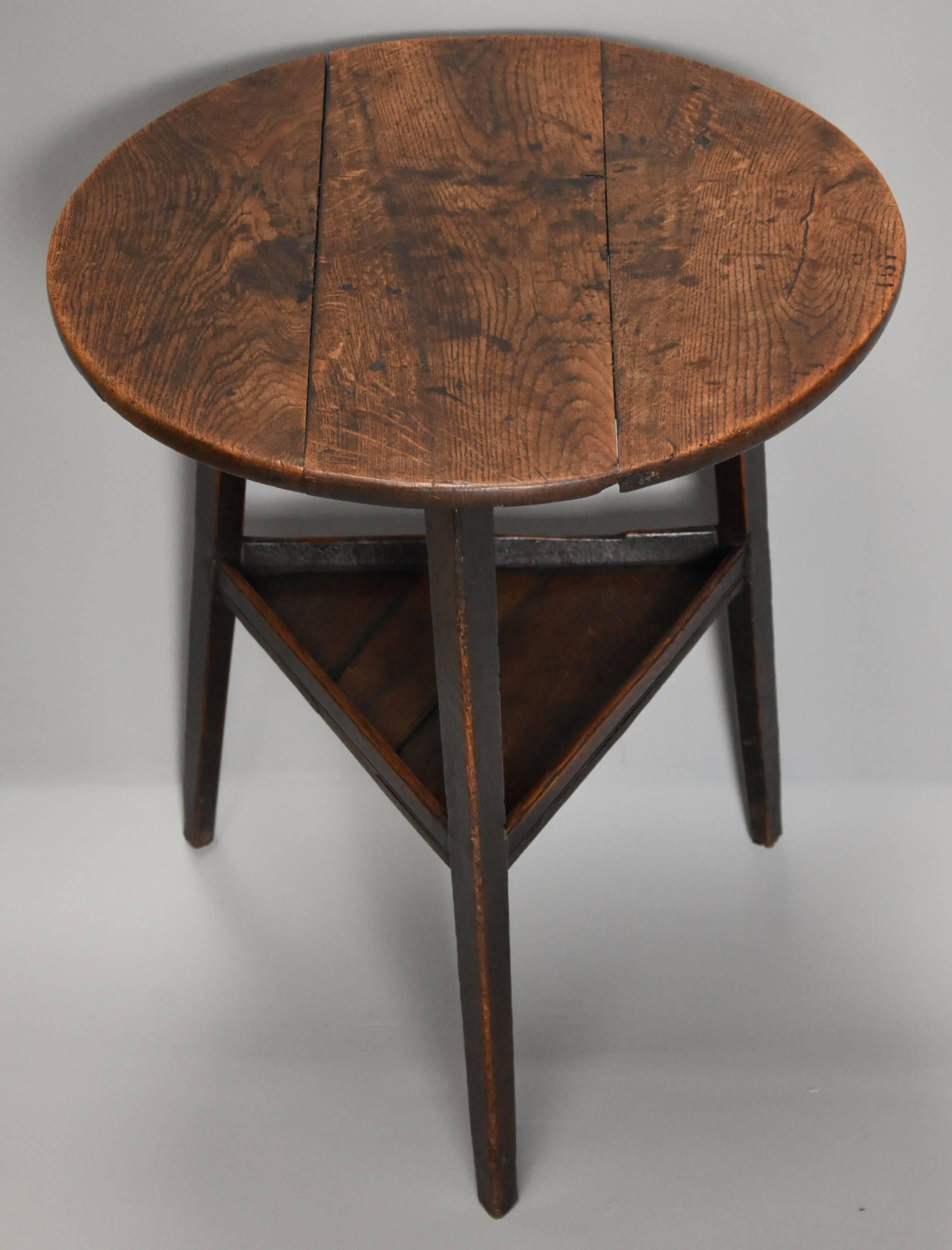 A superb late 18th century oak cricket table (or tavern table) with shelf below and of fine patina (color).

This table consists of an oak three plank top of fine patina, the top having an iron bracket below, this being an old repair.

The table