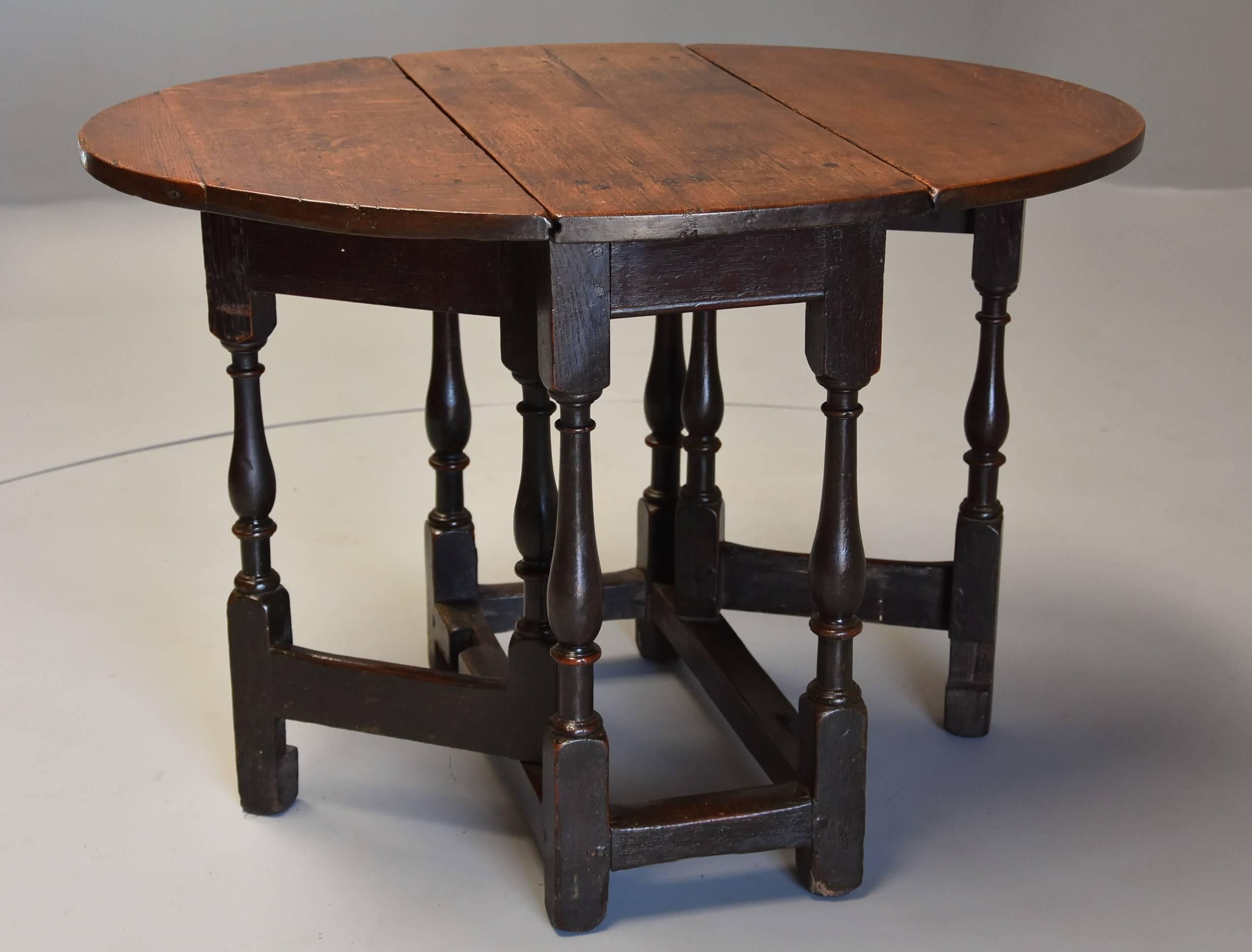 A late 17th century oak gateleg table of small proportions and good patina (color).

This table consists of an oak oval plank top of good color supported by finely turned legs and oak stretchers and would comfortably seat four.

This gateleg