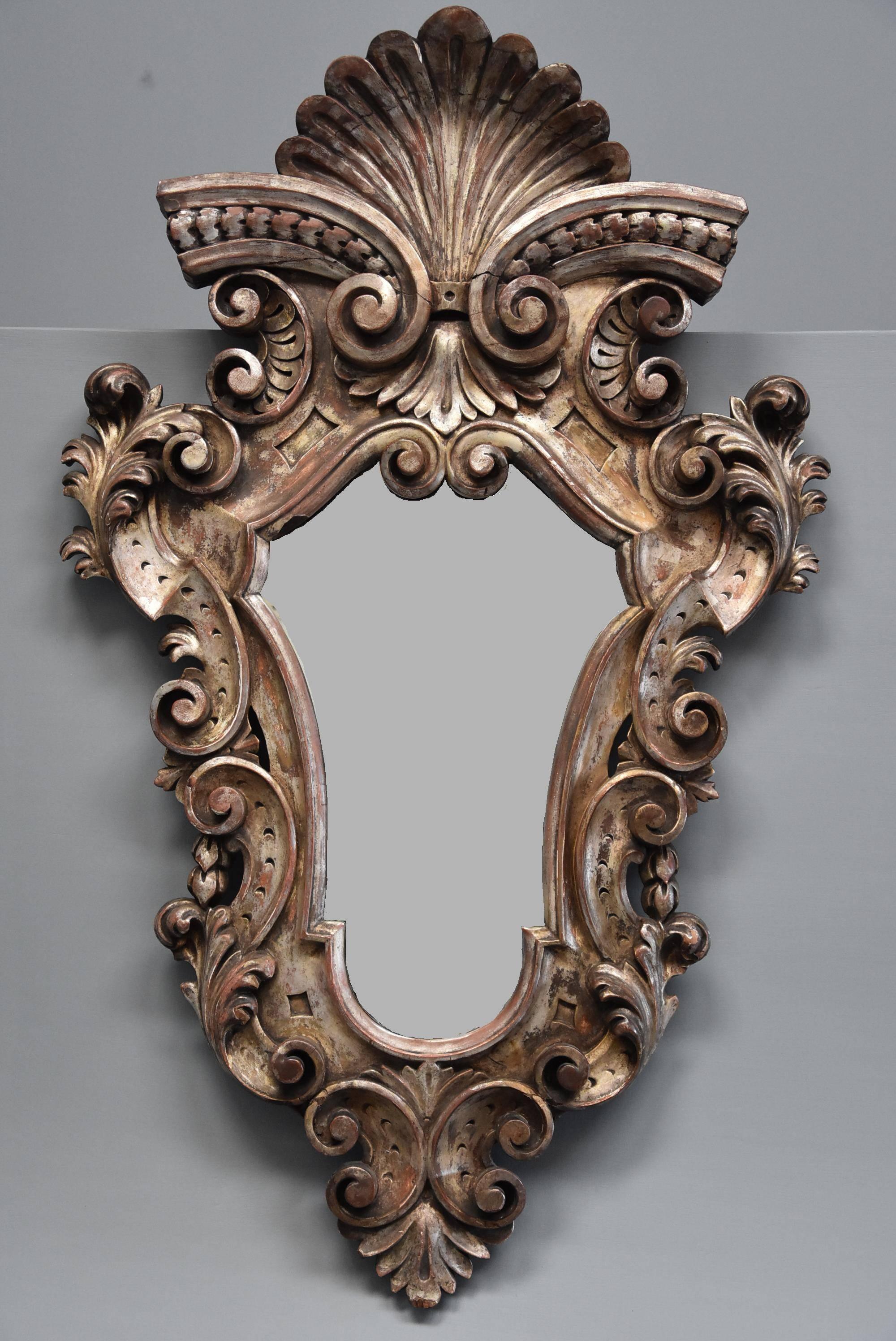 A highly decorative late 19th century Italian silver giltwood Rococo style mirror.

The mirror consists of a highly decorative silver gilt pine frame of typical Rococo shape and design with central carved scallop shell to the top with carved