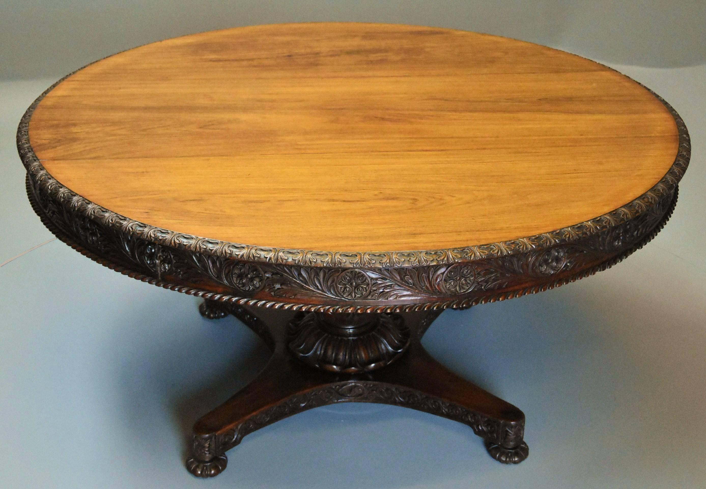 A mid-19th century large Anglo-Indian padouk superbly carved circular centre table.

This table consists of a solid circular padouk top of Fine, faded patina (color) with carved leaf edge leading down to a carved frieze with circular roundels and