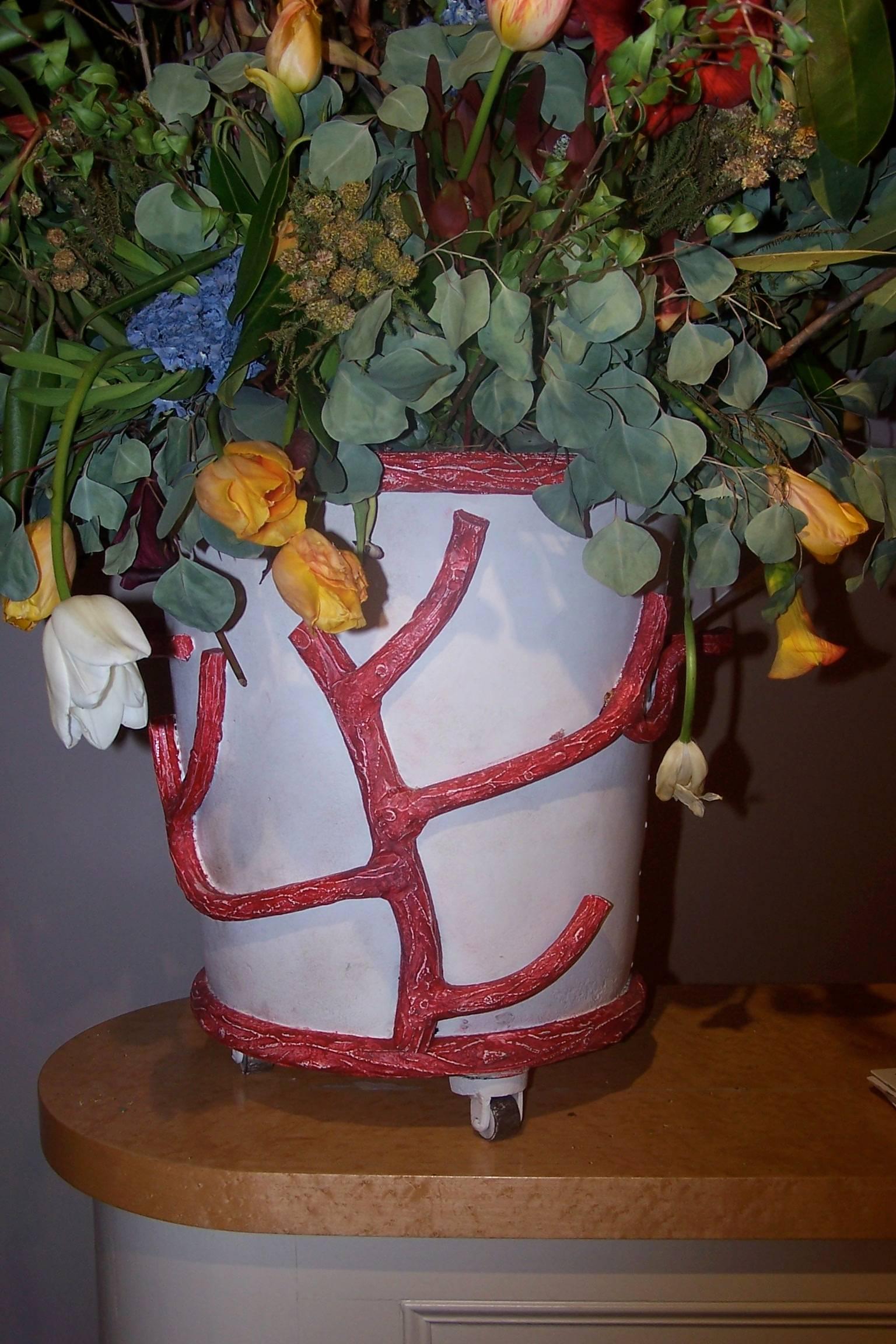 Painted iron and cast iron flower pot on castors.
Fallen branches serving as handles.