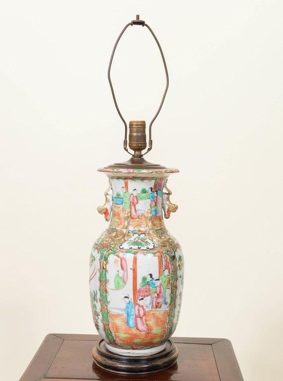 Chinese antique porcelain rose mandarin vase lamp. The antique vase wired from the top brass fitting leaving the vase intact and not drilled. Sitting on a separate Chinese turned wood stand. 
Good hand-painted figures in a landscape of birds and