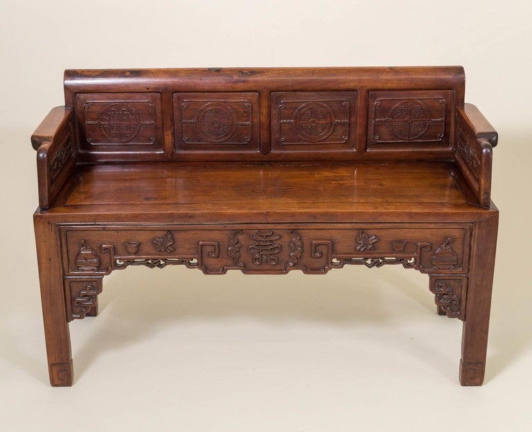 Chinese rosewood, (Hong Mu ), diminutive bench. Auspicious coin like medallions in high relief carved into four panels on the back. The same panels bordered by an eternal knot and cord design. Panels under the arms decorated in relief carving as