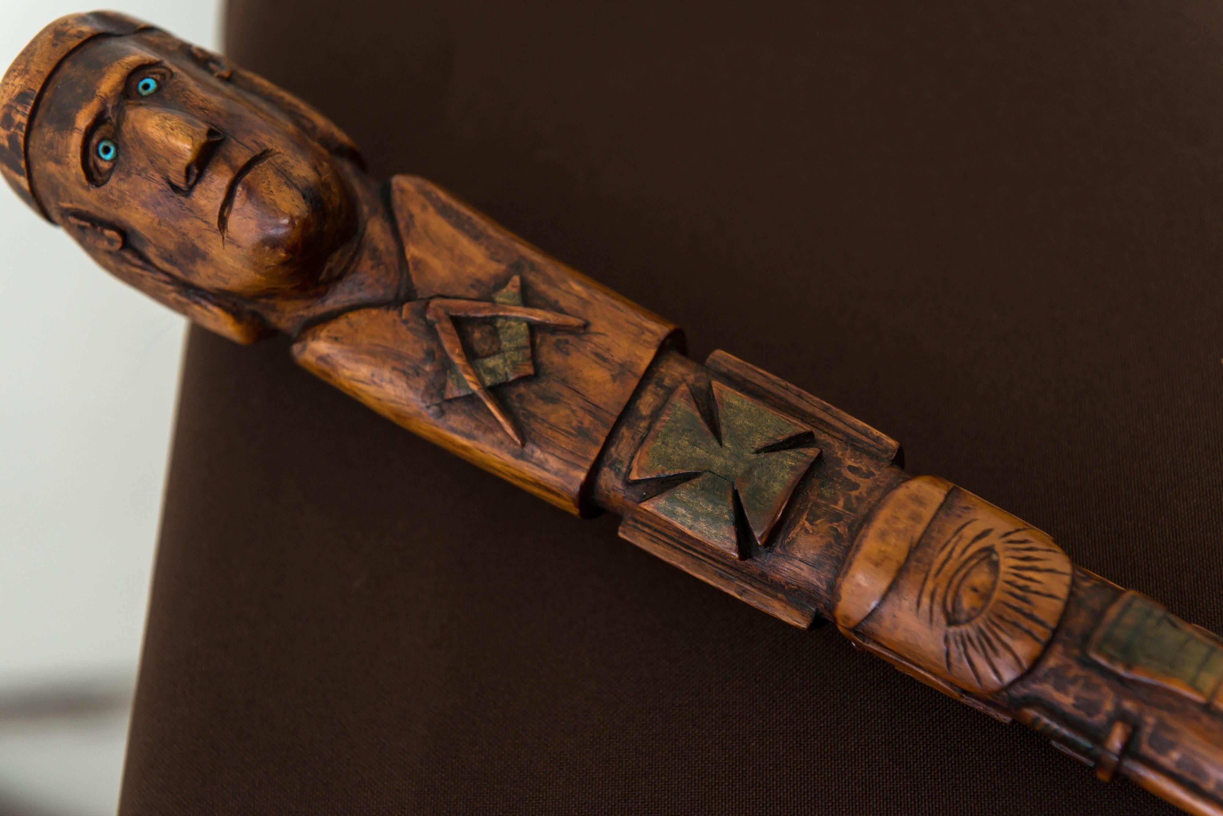 A late 19th century American Folk Art Masonic cane or stick, circa 1890.
Elaborate relief carved and polychrome Masonic icons cover all surfaces of the cane. The handle / top with a carved head of a fierce man with an intense gaze fitted with