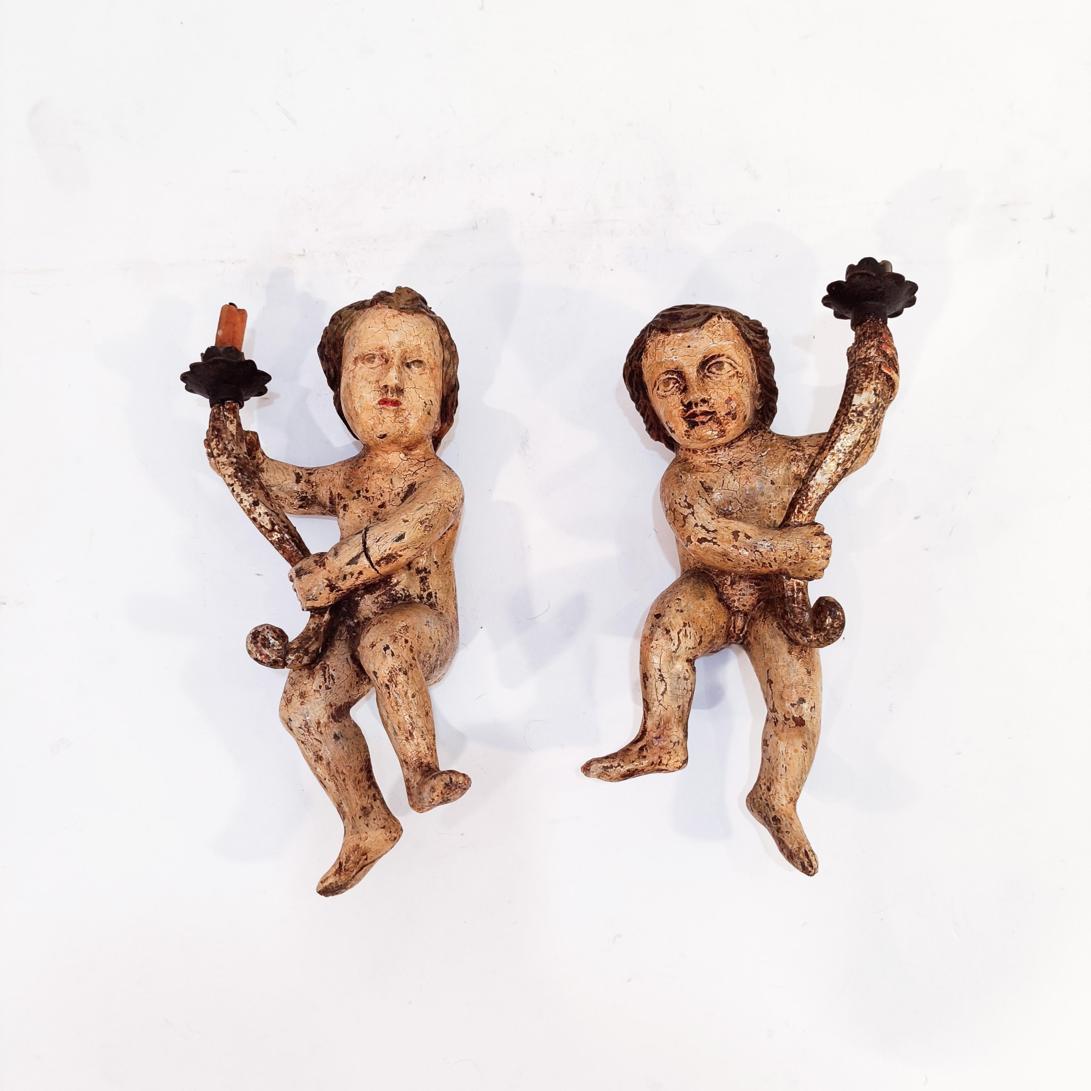 Pareja de querubines murales barrocos policromados, Spanish School, S. XVIII. Esculturas murales de madera tallada y policromada (posiblemente de nogal), que representan a dos querubines o ángeles torcheros desnudos, ambos sosteniendo una cornucopia