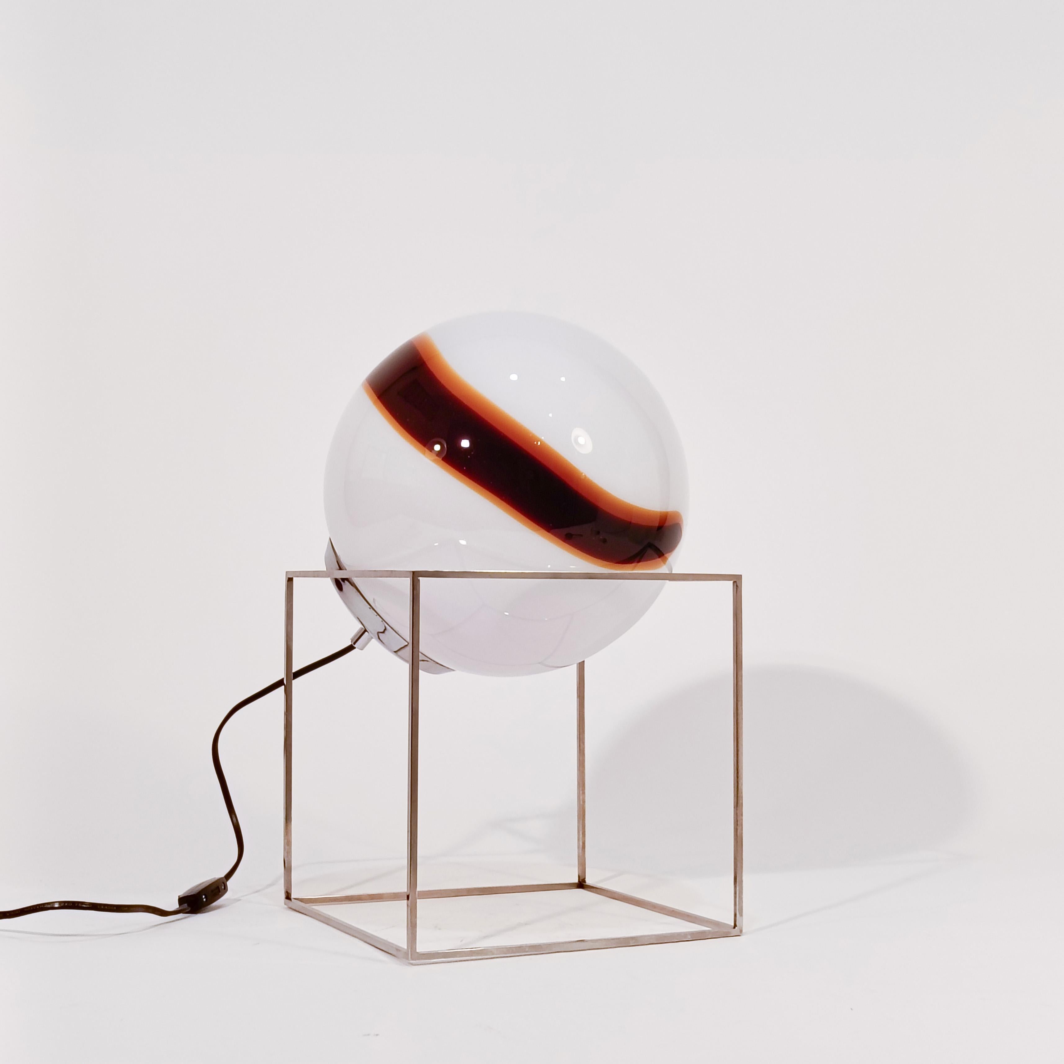 Lampe de table/plancher sculpturale en verre de Murano soufflé à la main dans le style de Venini, années 1970. Formée d'un cube en acier chromé qui accueille une sphère en verre de Murano blanc strié d'orange et de brun caramel, produisant un effet