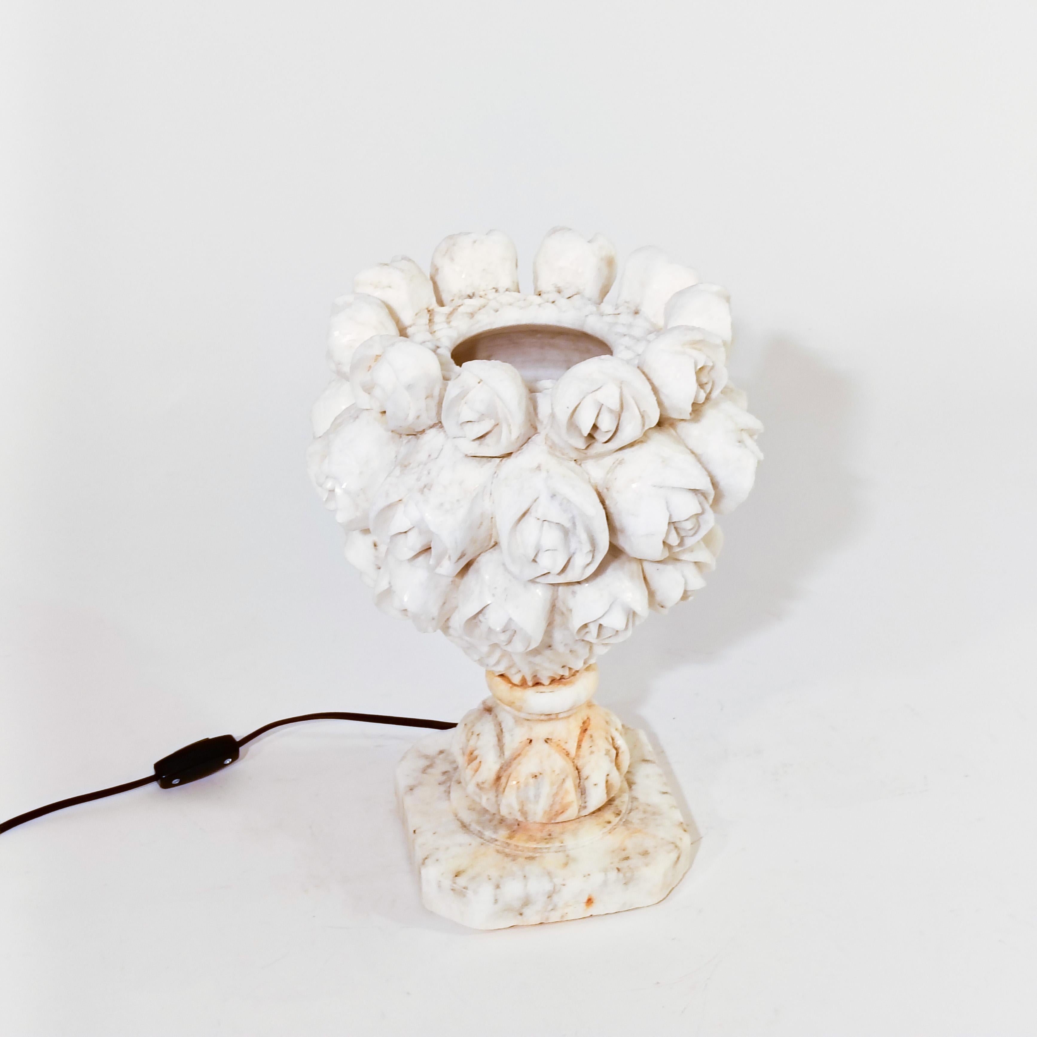 Handgeschnitzte Tischleuchte aus Alabaster, bestehend aus zwei zusammengesetzten Teilen: Sockel und Diffusor. Beide Stücke sind handgearbeitet und gedrechselt und bieten vegetabile Formen von Rosen, durch die das Licht gestreut wird und die eine