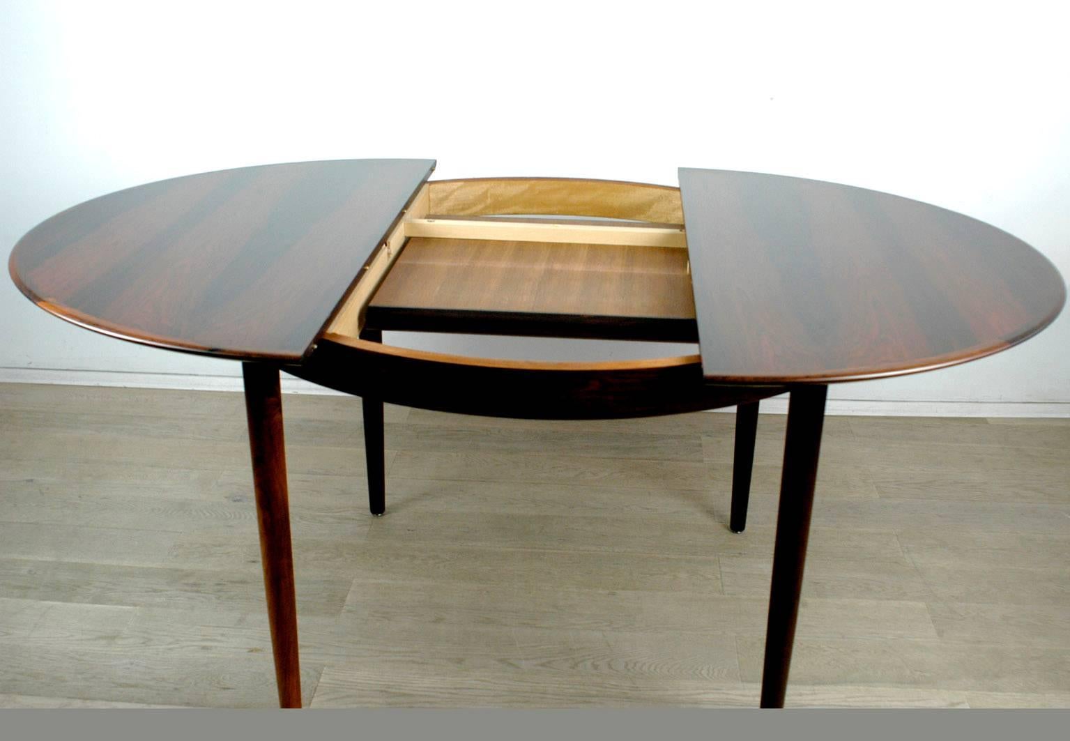 Circular Danish modern extendable dining table. Extensions are hidden under the table top and can be folded out easily.
 