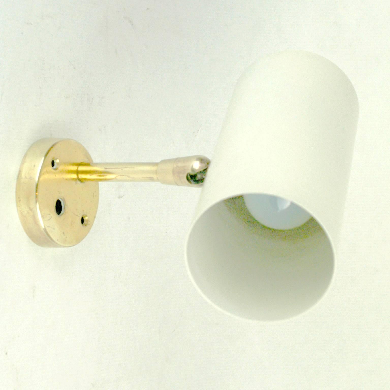 Pure and elegant Austrian Midcentury brass wall light with white lacquered zylindrical metal shade, which can be adjusted into different positions designed by J. T. Kalmar for Kalmar Vienna in the 1960s