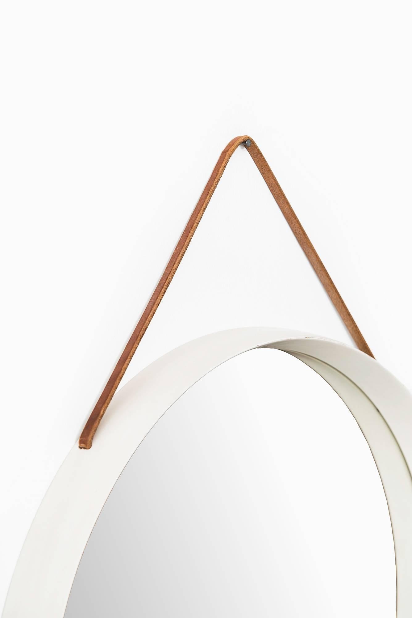 White lacquered round mirror with leather strap produced in Sweden.