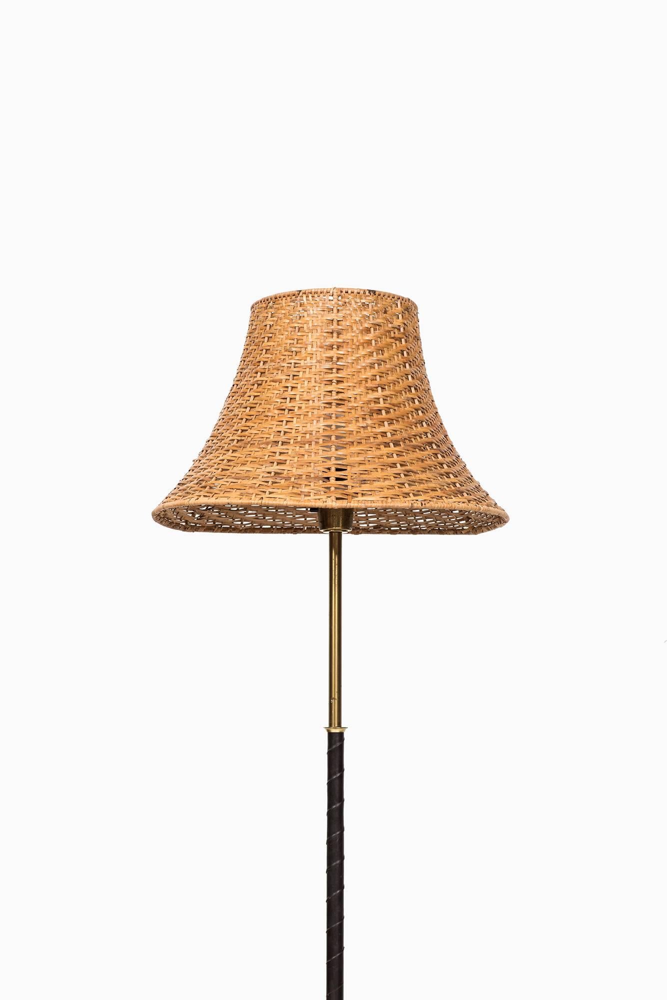 Floor lamp in black leather, brass and woven cane shade. Produced in Sweden.