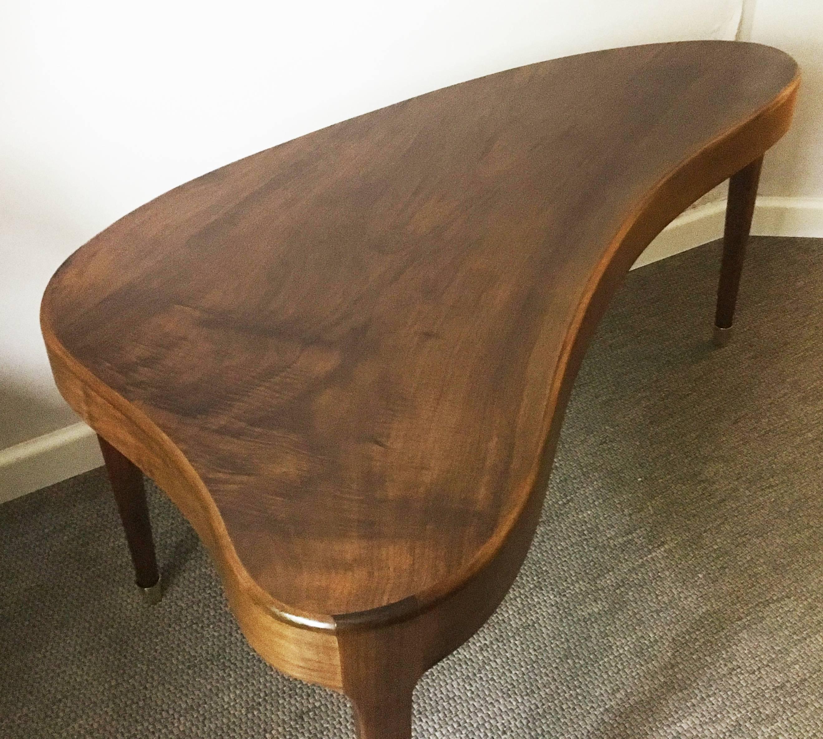 Elegant Mid-Century kidney shaped walnut coffee table. Legs with brass ends.
 