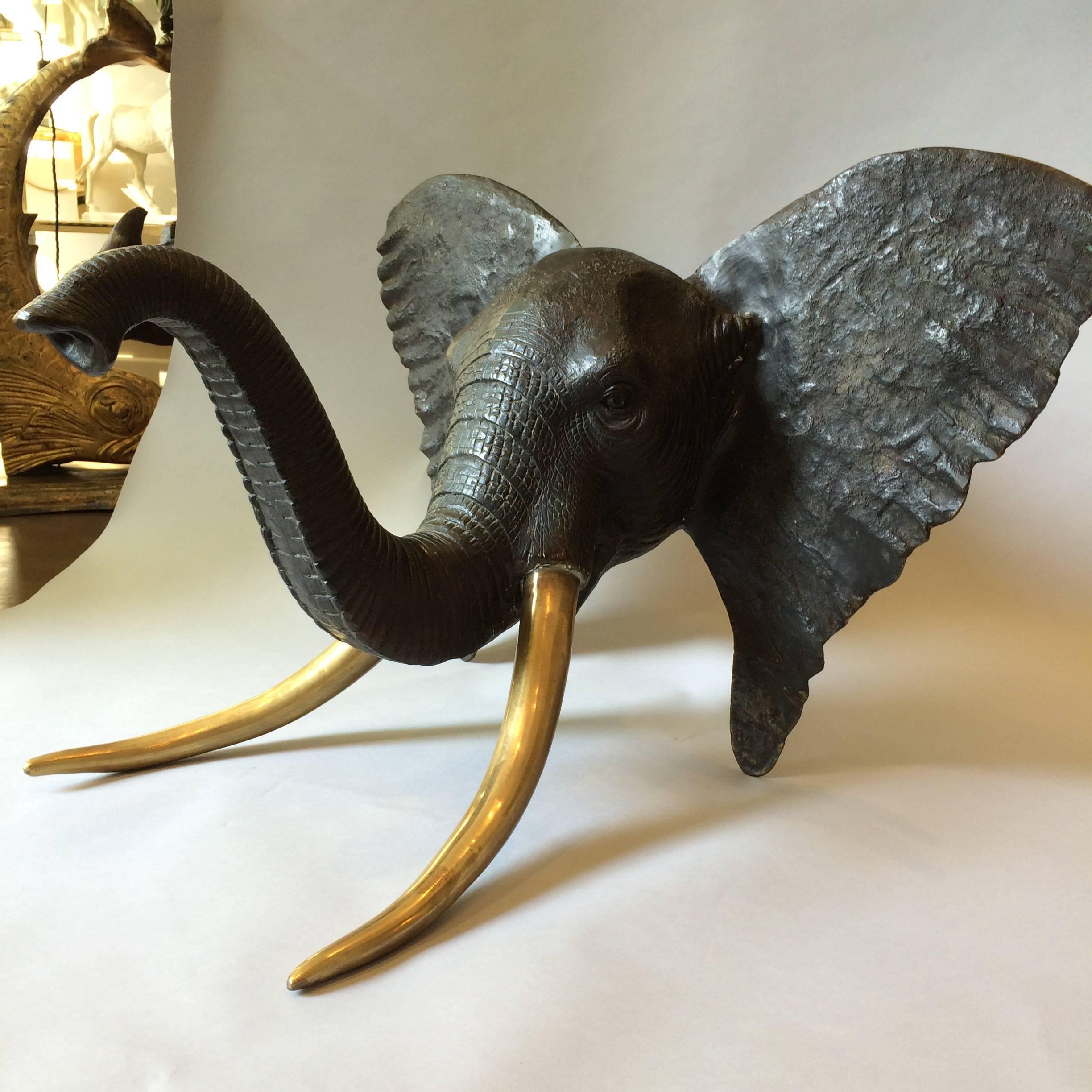 Huge bronze elephant head sculpture with brass tusks.

 