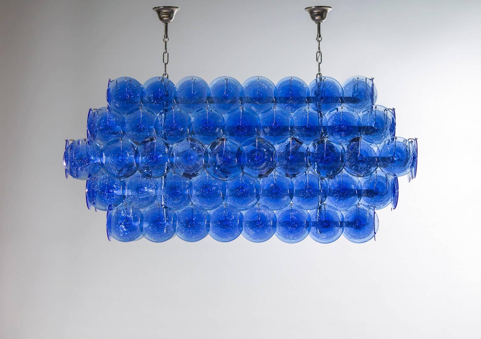 Amazing and spectacular Italian Murano chandelier, attributed to Mazzega, circa 1980s, composed by circular elements in blue color with in the center bubbles submerged, all is supported by a chrome frame. The chandelier is 26 inches high without