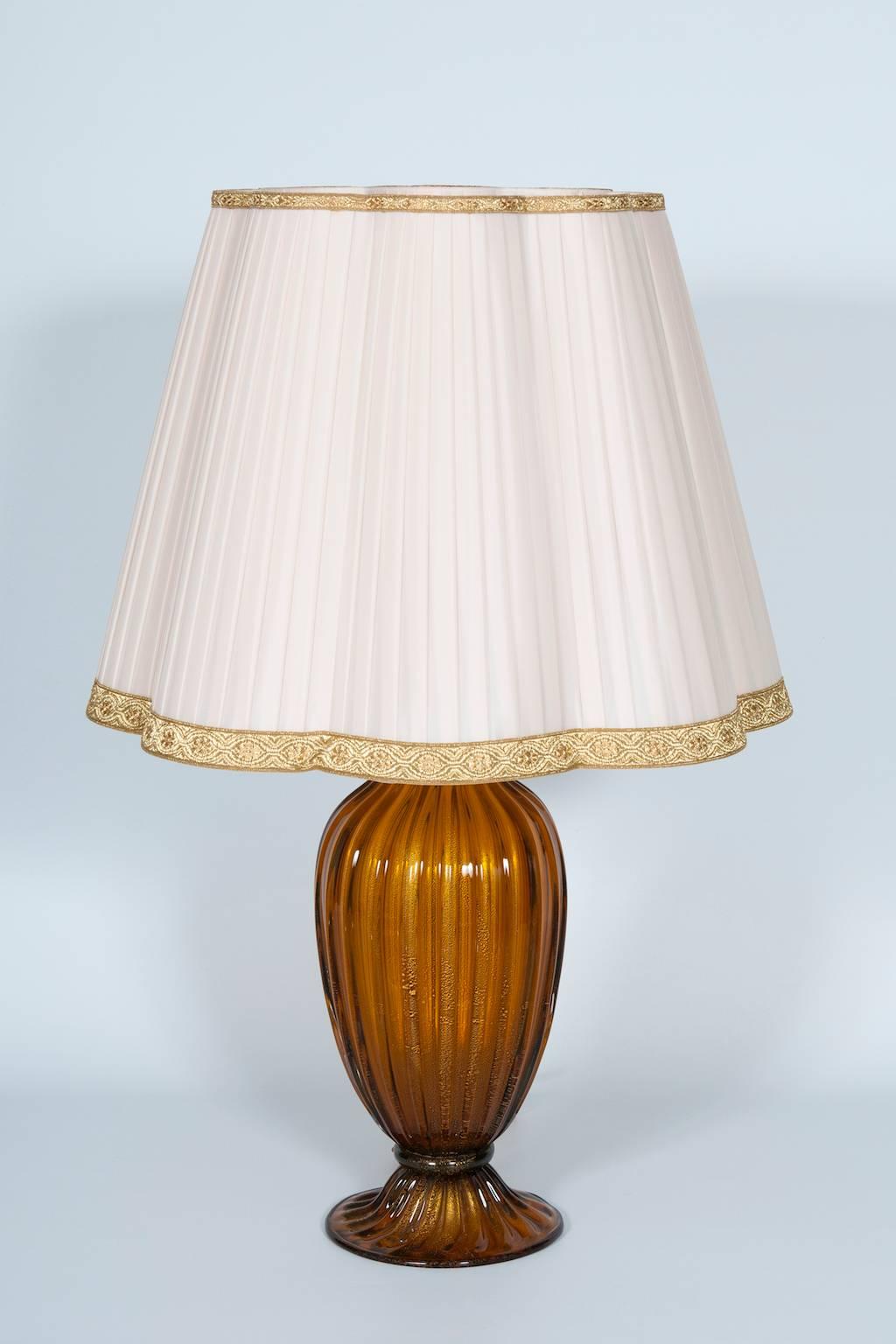 Elegant Italian Venetian Table Lamp in Blown Murano Glass, by Gabbiani, Amber Color with Gold Finishes, 1970s.
This is a uniquely refined work of art, entirely handcrafted in blown Murano glass in the Venetian island of Murano. The central body and
