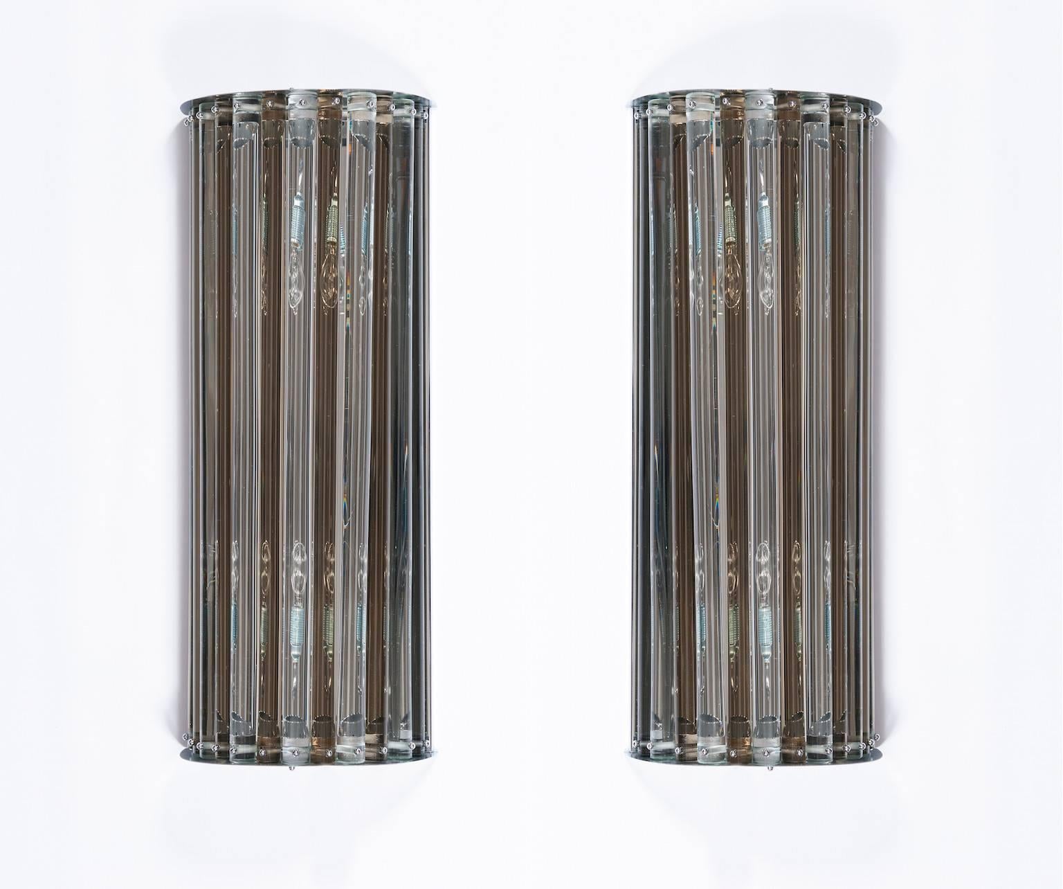 Paire d'appliques italiennes en verre de Murano, en très excellent état d'origine vers les années 1980, composées d'éléments cylindriques en verre transparent et fumè (Fumè est la couleur de la fumée), avec un cadre chromé d'origine. Les appliques