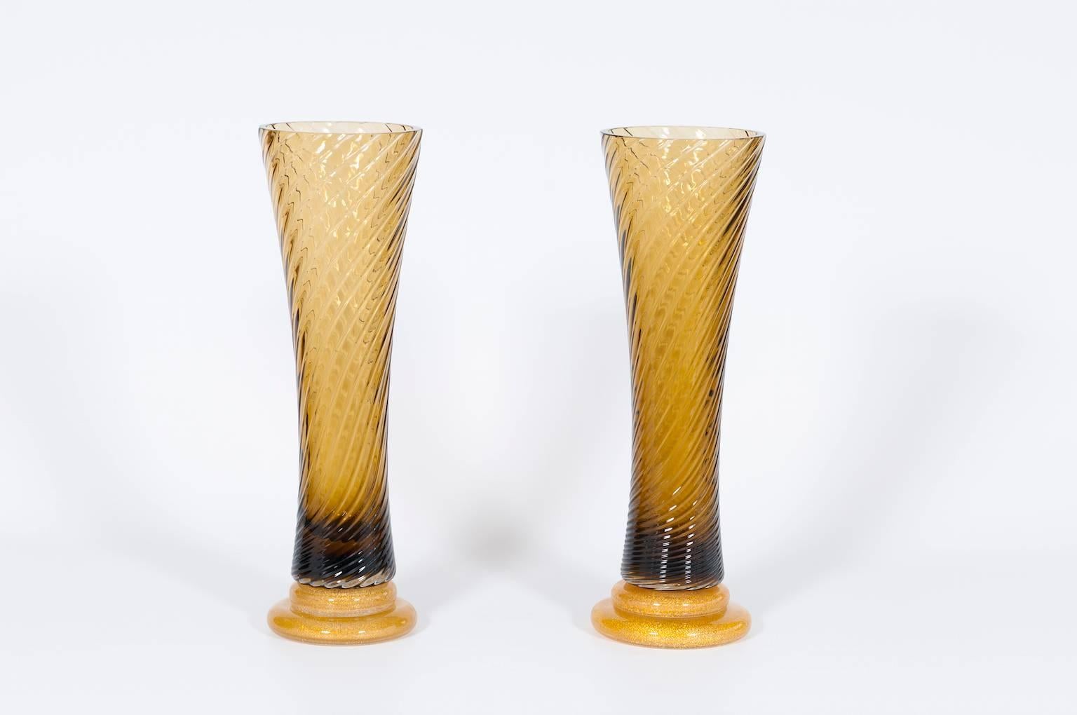 Giant Pair of amber Glasses Vase in blown Murano Glass 1980s.
Pair of elegant Italian Murano glass vases in amber and gold. Fine and very thin and long amber glasses in a twisted handcrafted blown Murano glass coupled in a gold basement entirely