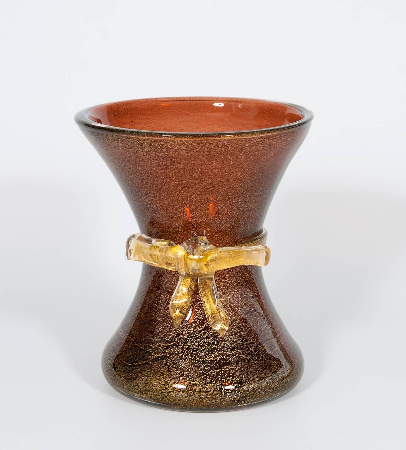 Vase with Bow Amber color  and gold finishes in blown Murano glass  1970s Italy
Elegant Italian Murano glass vase in gold and amber color with a beautiful gold tape in the middle. The vase is 10.63 inches high, by 9.06 inches diameter.
This