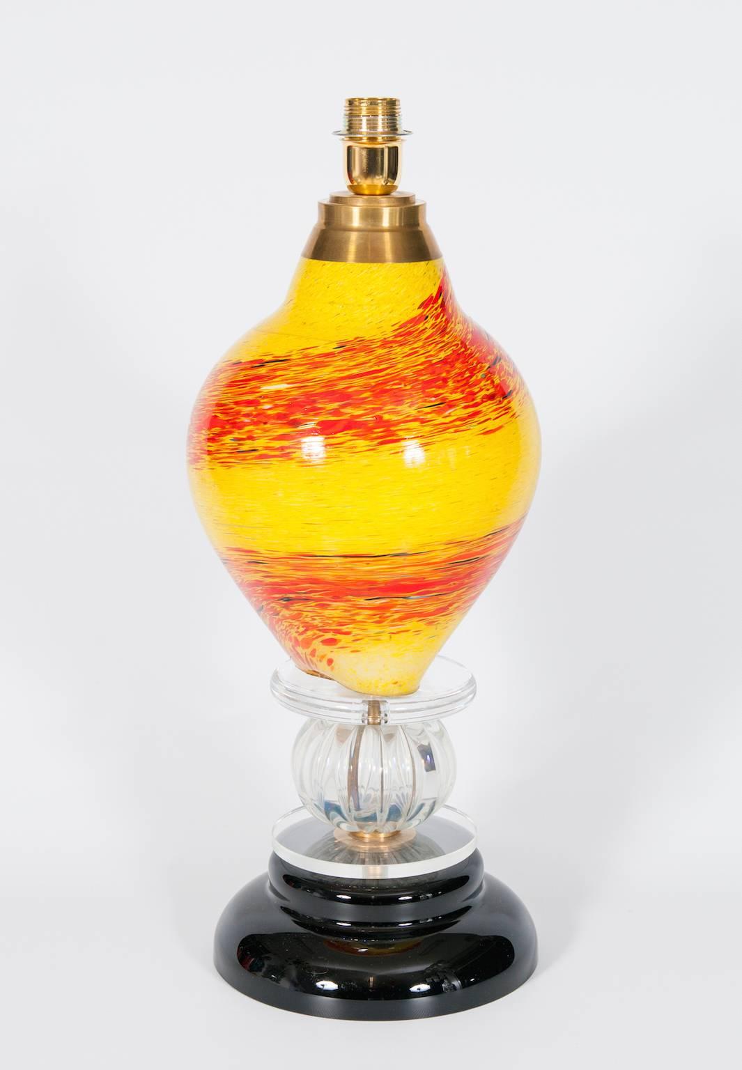 Lampe de table italienne en verre vénitien de Murano avec une base noire au dessus de deux rondelles avec au milieu une sphère, et au dessus un bol fantastique dans les couleurs jaune et orange. La lampe de table est entièrement réalisée à la main