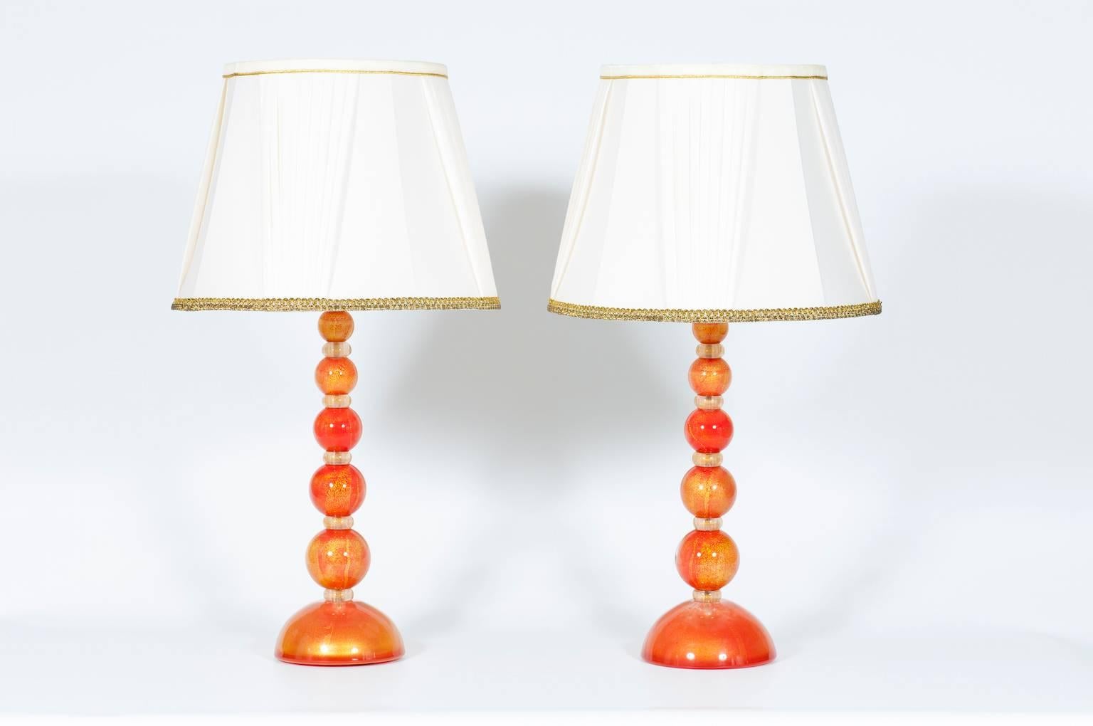 Pair of very particular Italian Venetian Murano glass table lamps in gold and orange, in very excellent original condition from 2016, having a base and a spheres in orange and gold with between them a gold washers. The table lamps measure 21.46 inch