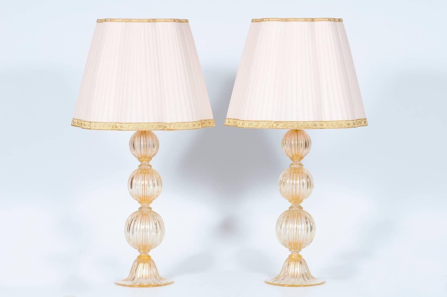 Elegant pair of Italian table lamps in Murano glass 24-carat gold, composed of a base, and from three spheres, in 24-carat gold Murano glass with stripes. All parts were made and realized in the Murano island, circa 1980s by blowing and handmade.