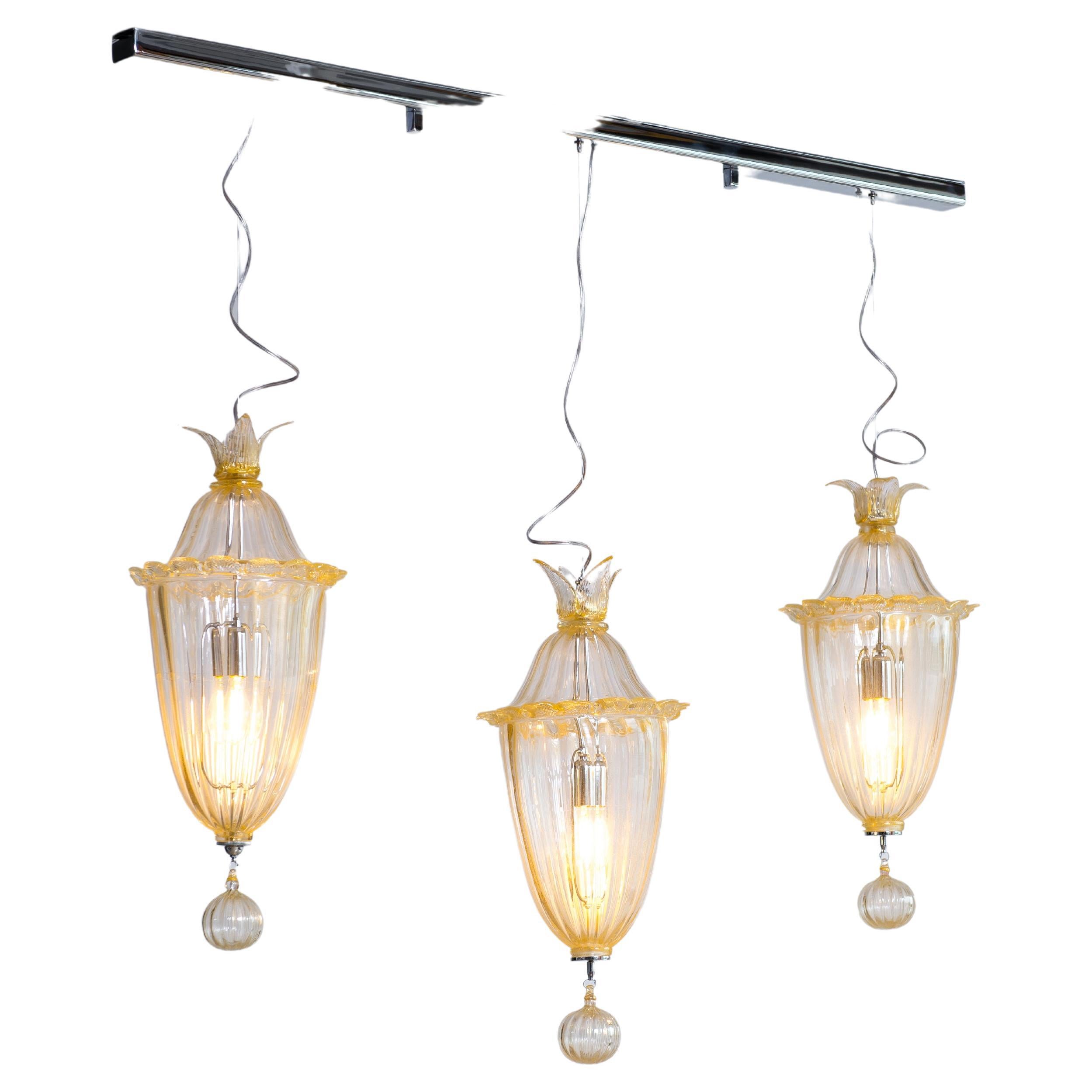 Suspension Lamp with Gold Finishes in blown Murano Glass Contemporary Italy
The chandelier holds three transparent Murano glass Cesendelli ( suspensions ) with gold finishes. The three Cesendelli are set at two different heights, and fixed to the