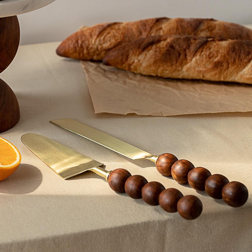 An elegant and unconventional set, this solid wood cake knife and server duo is thoughtfully paired with our signature Ball Cakestand. Handcrafted from high-quality wood, the set includes two beautifully shaped knives—measuring 13