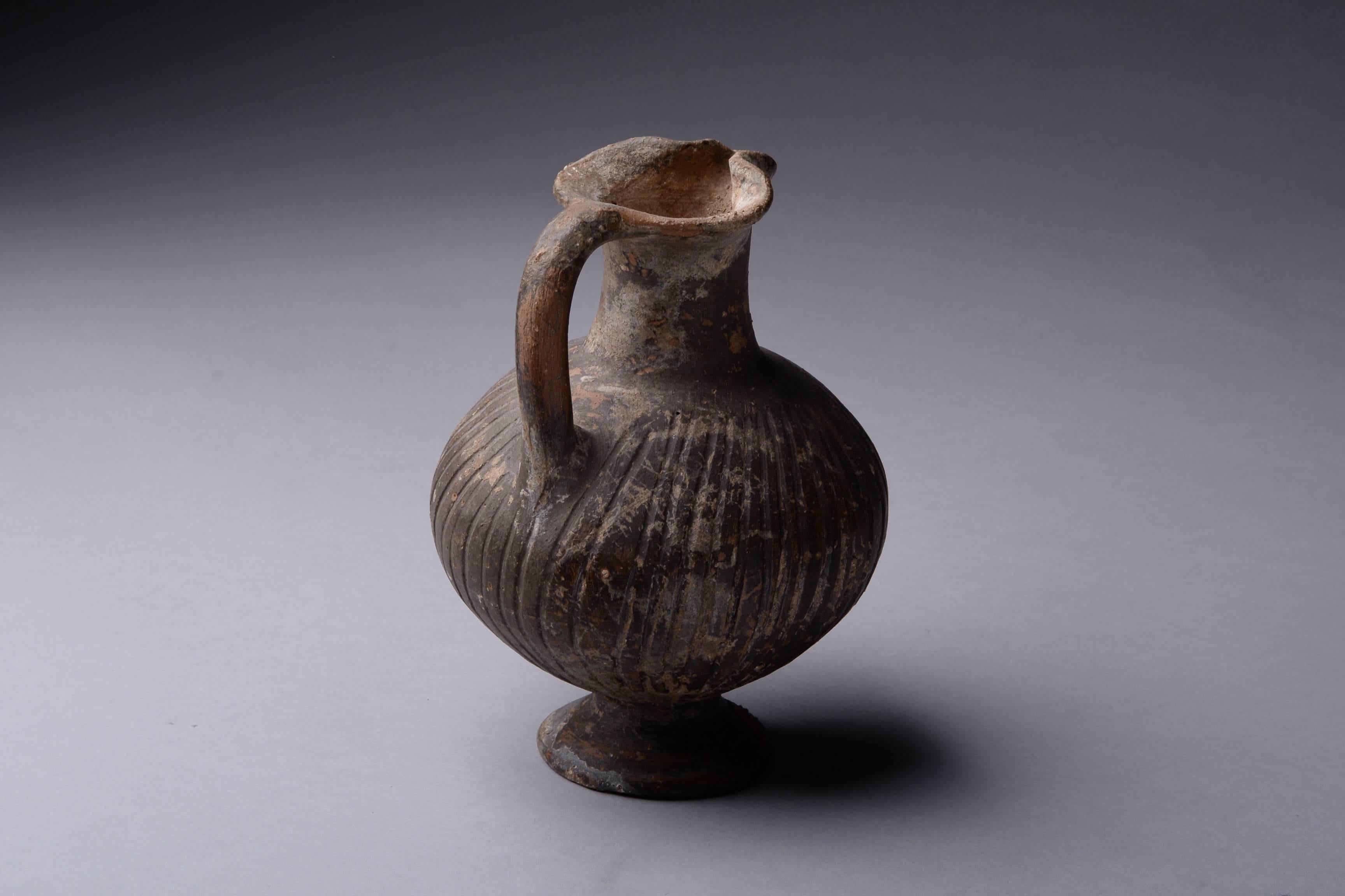 A fine example of an ancient Cypro-Geometric black slip ware jug, dating to circa 950-800 BC. These characteristically Cypriot vessels are sometimes referred to as black slip ware jugs. They are characterized by the globular body with grooves,