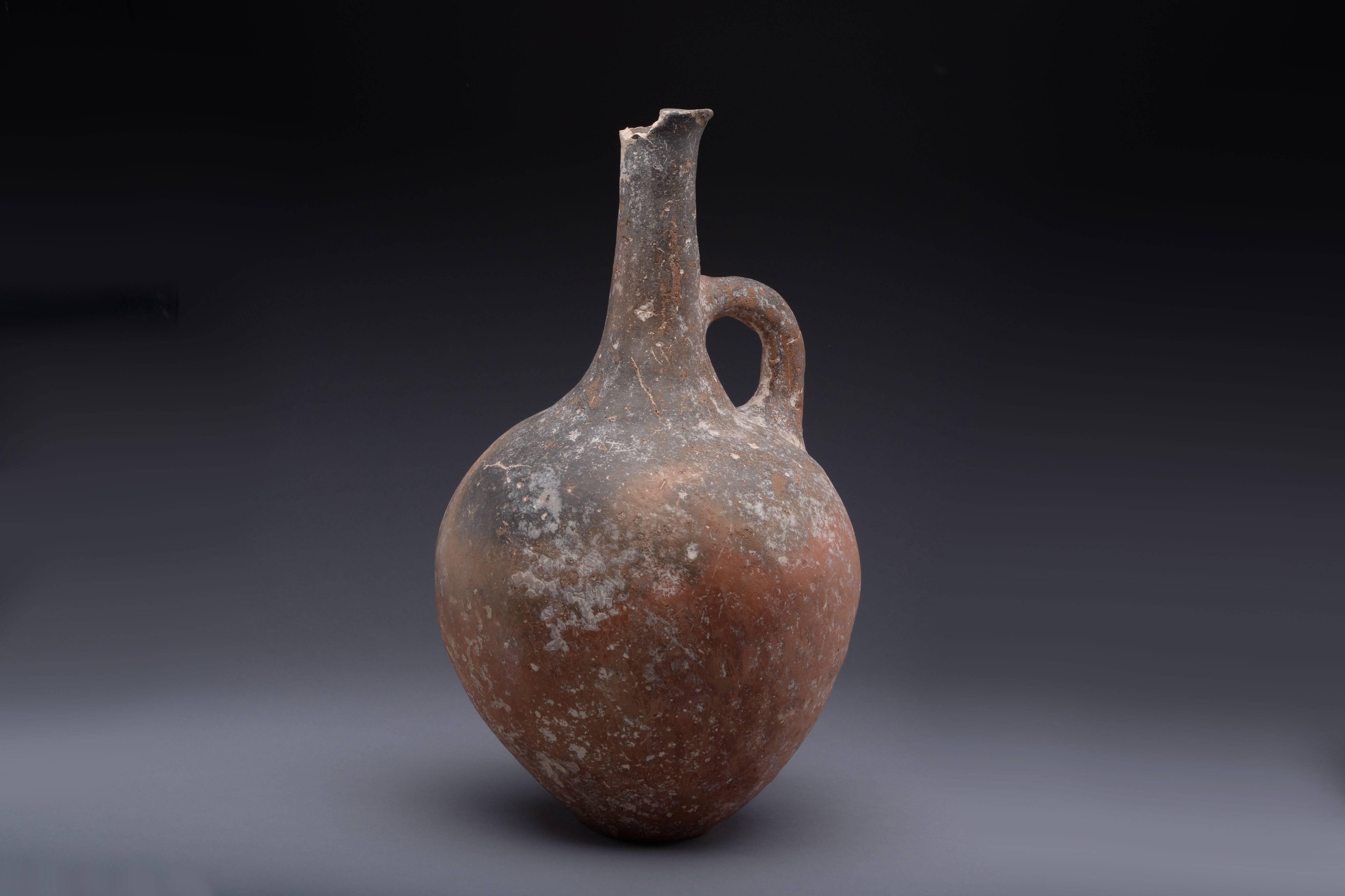 A large and handsome Cypriot Early Bronze Age jug, dating to around 2400 BC.

Of typical burnished red ware, with plump, rounded body, tall cylindrical neck and loop handle. 

Provenance:

Collected by Leon Rodrigues-Ely, 1924 – 1973. 

Leon