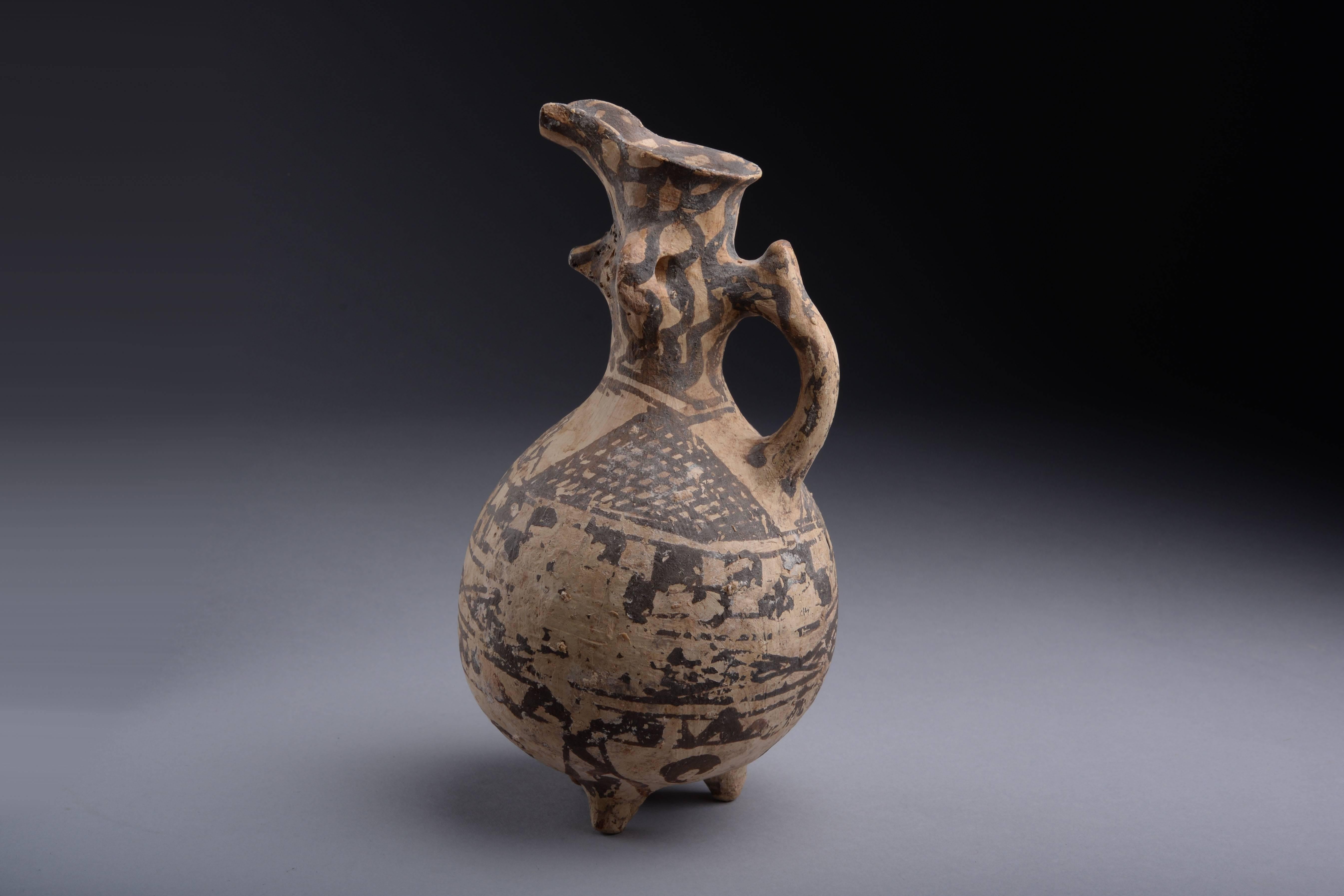 An exceptional Middle Bronze Age Cypriot ceramic of clearly anthropomorphic form.

The ceramic has an ovoid body, which stands on three stubby legs, a short cylindrical neck, funnel spout and loop handle at the back. A protuberance represents the