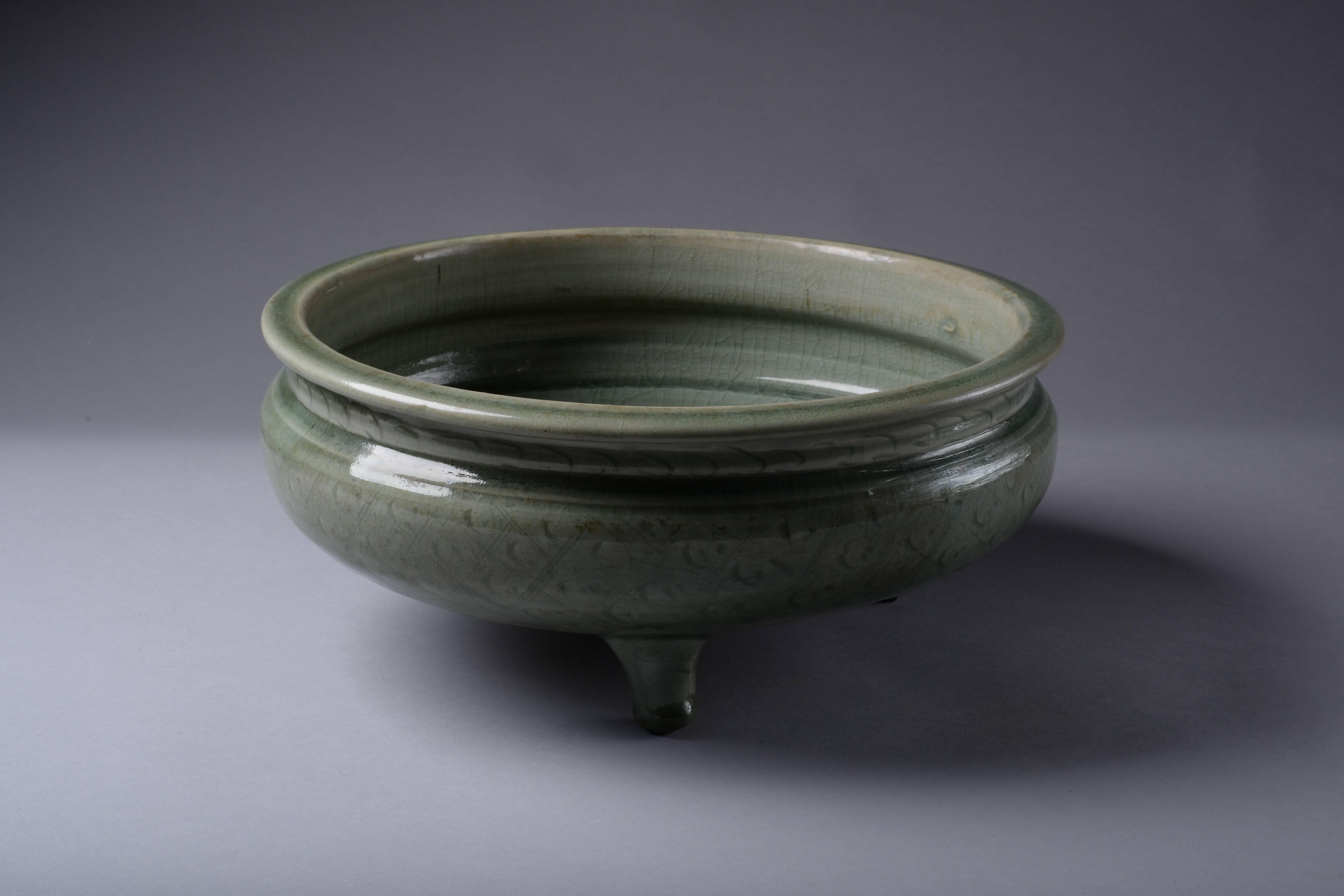 A beautiful Ming dynasty celadon glazed tripod censer, used for burning incense, from the Longquan kilns and dating to the 14th-17th century.

The large shallow bowl with a short but wide neck, everted rim, circular base and three cylindrical
