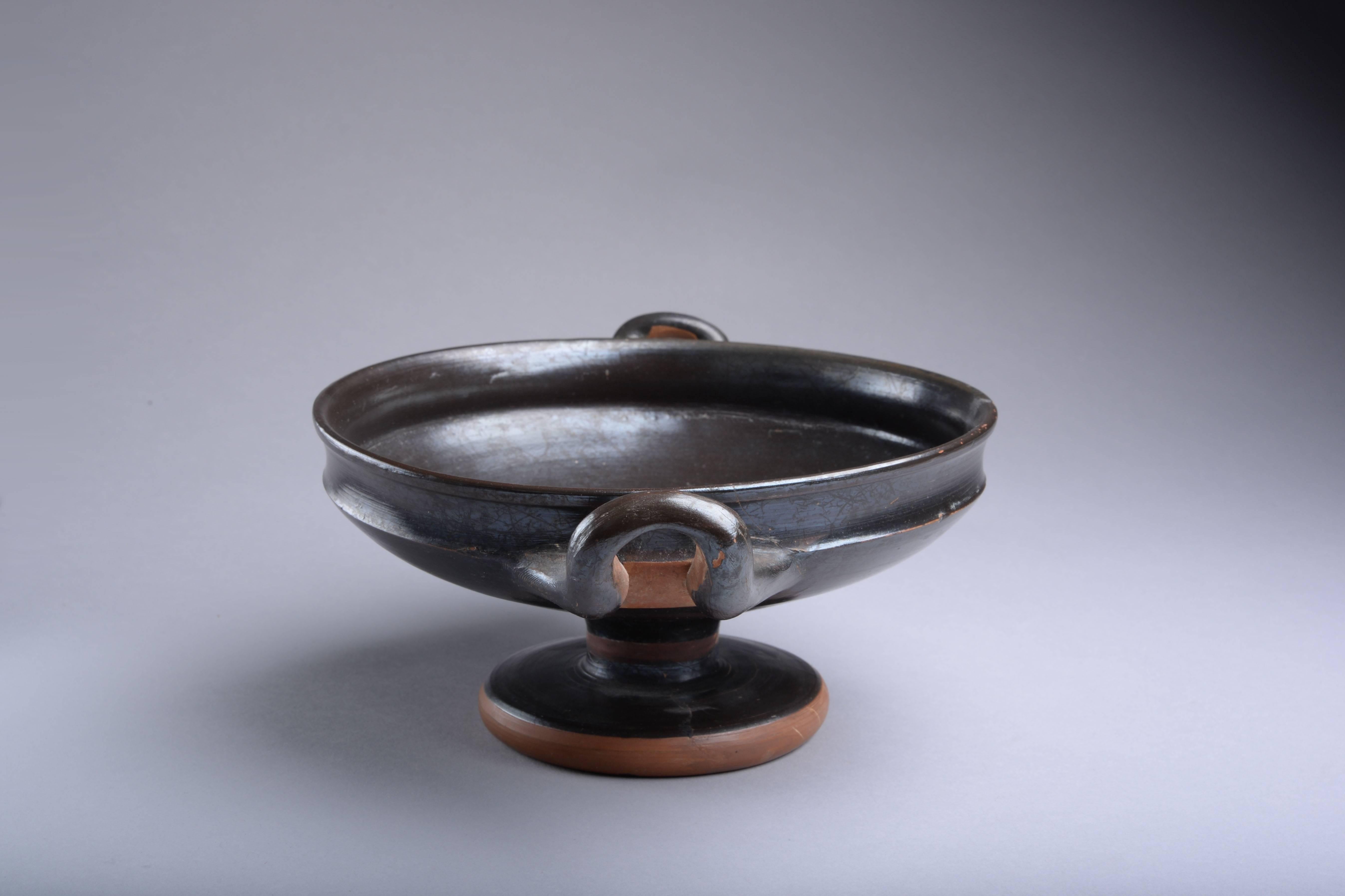 An elegant ancient Greek black glazed ceramic kylix, produced in Athens, circa 4th century BC.

A beautiful, decorative vessel, of pleasing form, decorated throughout with a magnificent smokey black glaze. 

Kylikes were used during drinking