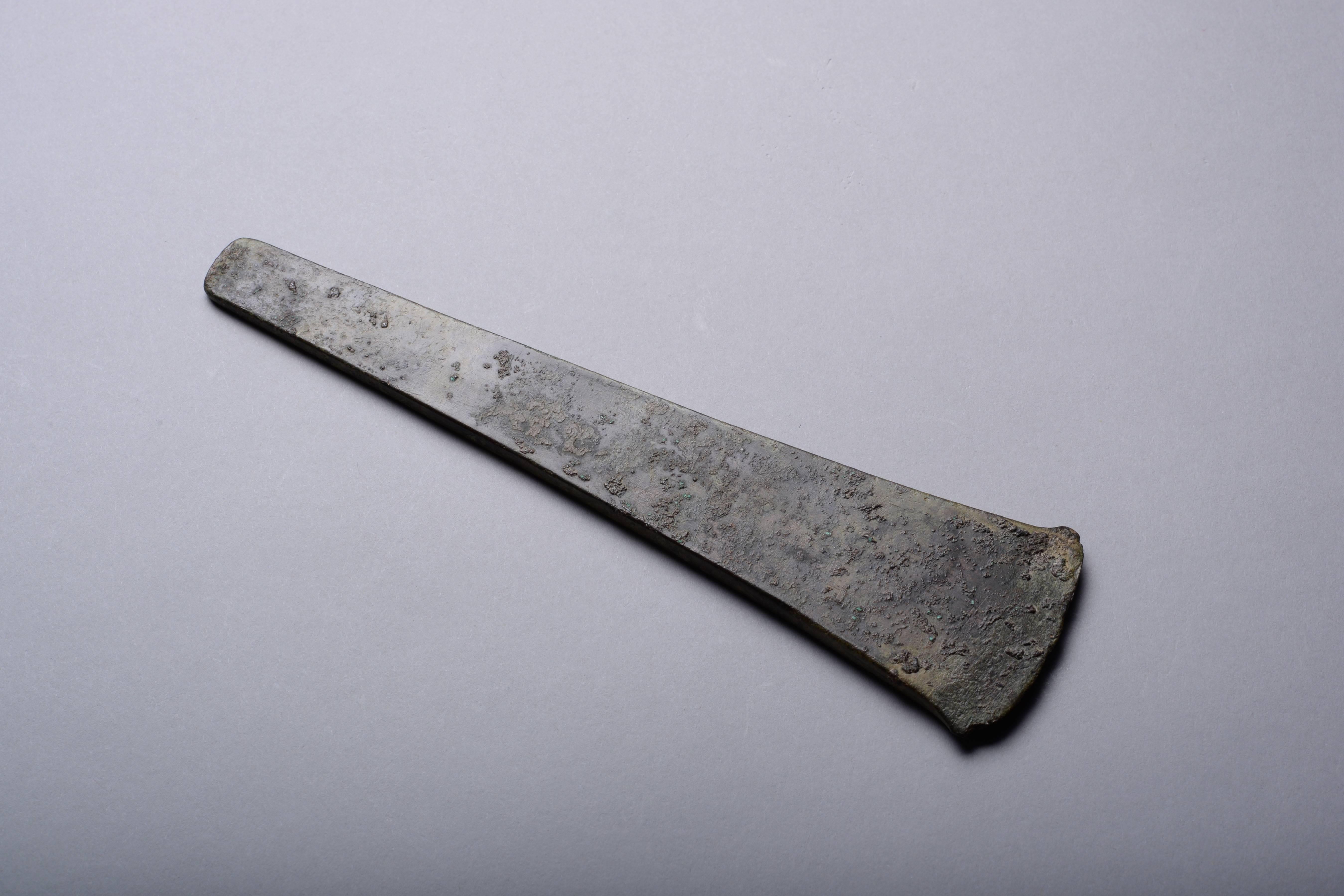 A rare ancient European bronze age flat axe of early form, dating circa 2300-2000 BC.

This Bronze Age axe is of striking form, with subtly curved blade edges tapering into a long neck. Its style suggests it dates to the Mount Pleasant phase of