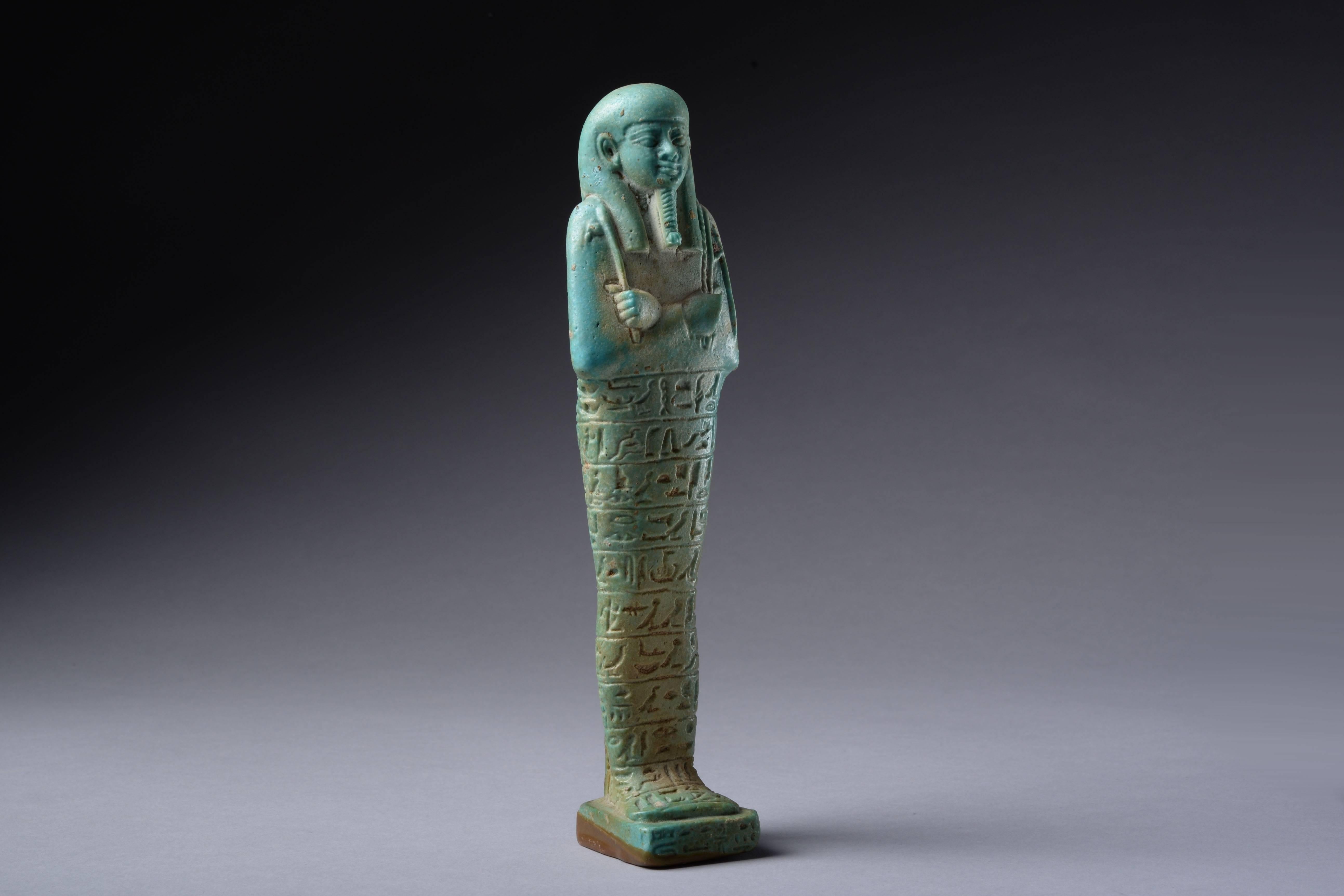 A beautiful, perfectly preserved and well provenanced ancient Egyptian blue-green faience shabti for Tjanehebu, overseer of the Royal Ships, dating to the 26th dynasty, the reign of Amasis II, 570 BC.

Of typical mummified form, with tripartite