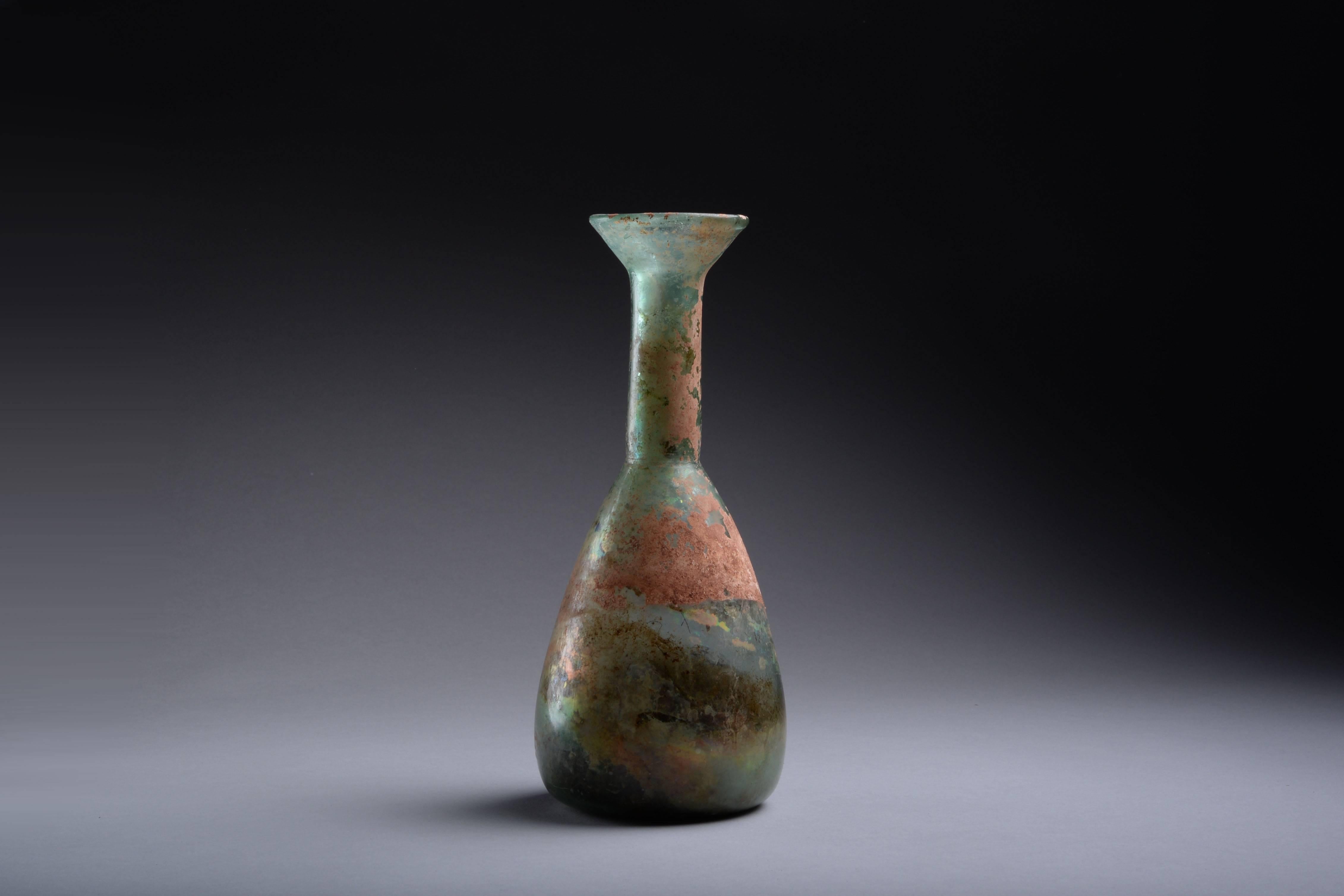 An elegant ancient Roman glass bottle, dating to the 2nd century AD.

The pear shaped body rises into a tall, cylindrical neck, with splayed mouth. Exhibiting wonderful iridescence and original encrustations throughout.

Provenance:

Ex.