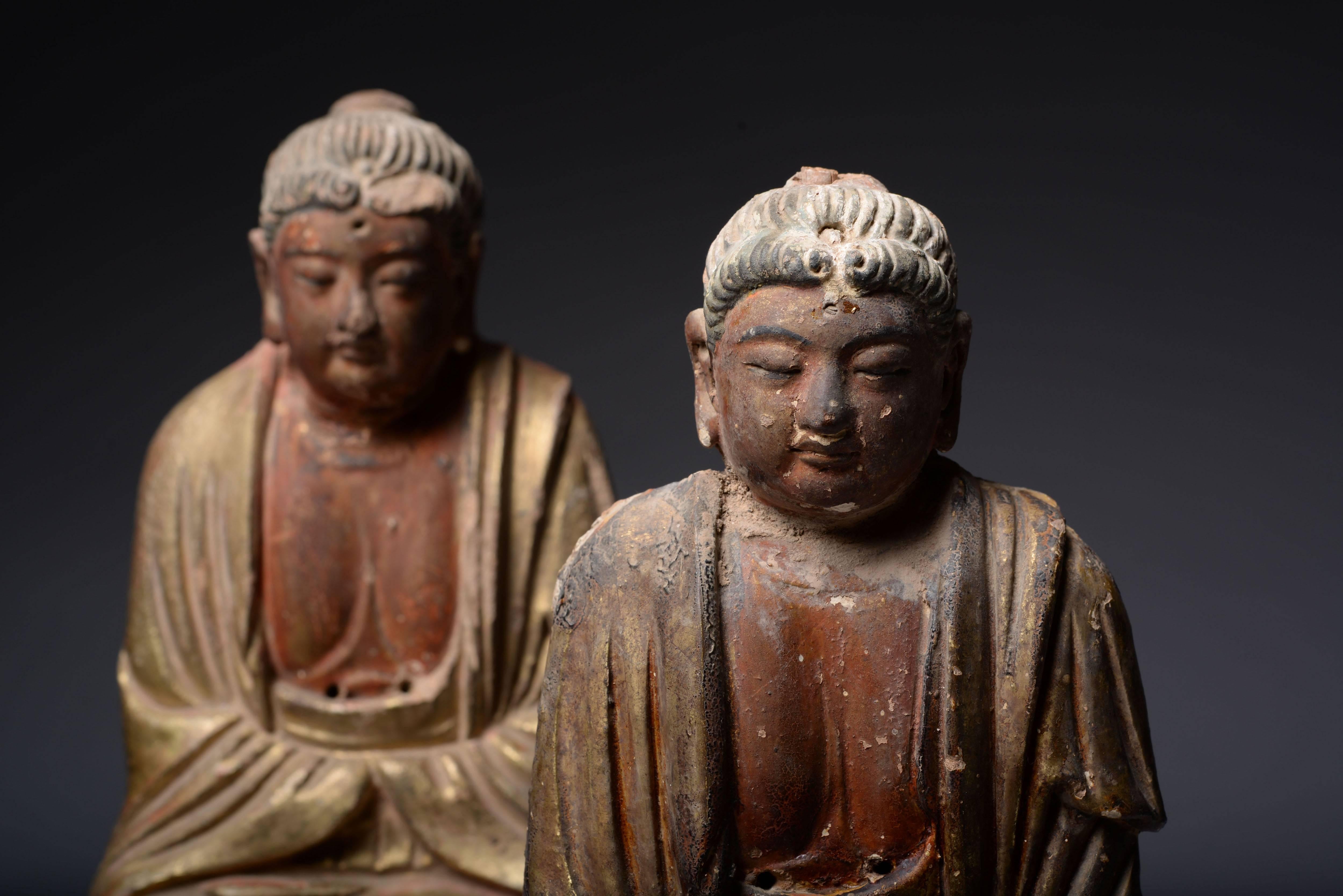 A pair of Chinese Yuan - early Ming dynasty parcel gilt painted terracotta figures of Buddha, dating to approximately 1275 – 1400 AD.

These beautiful and elaborate figures of Buddha are relatively unusual examples of medieval Chinese art, being