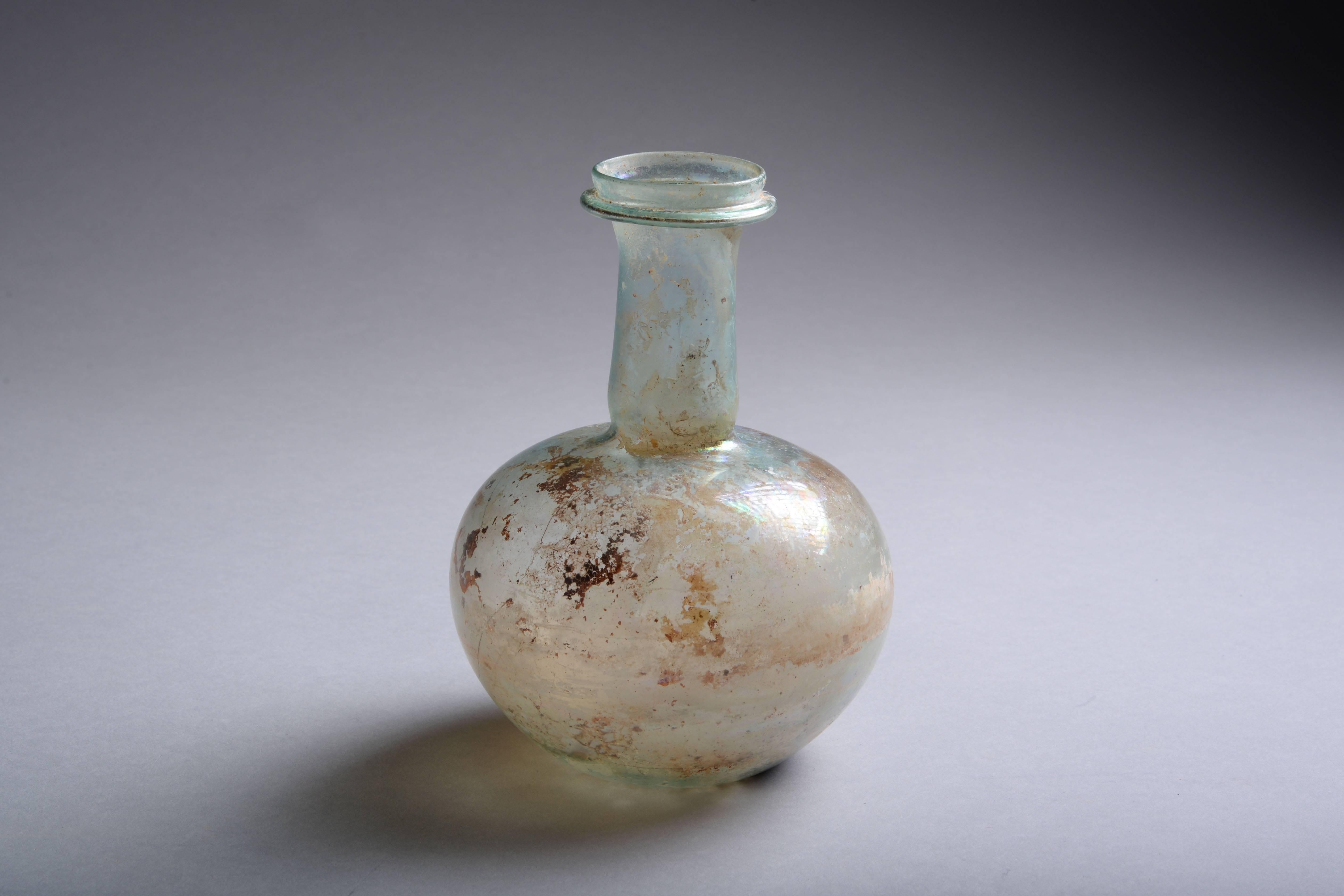 An elegant ancient Roman glass bottle, dating to the 2nd century AD.

The rounded body rises into a tall, cylindrical neck, with collared lip. 

A fine piece of ancient glass, in excellent condition.


Height 6 inches,

width 4 1/2