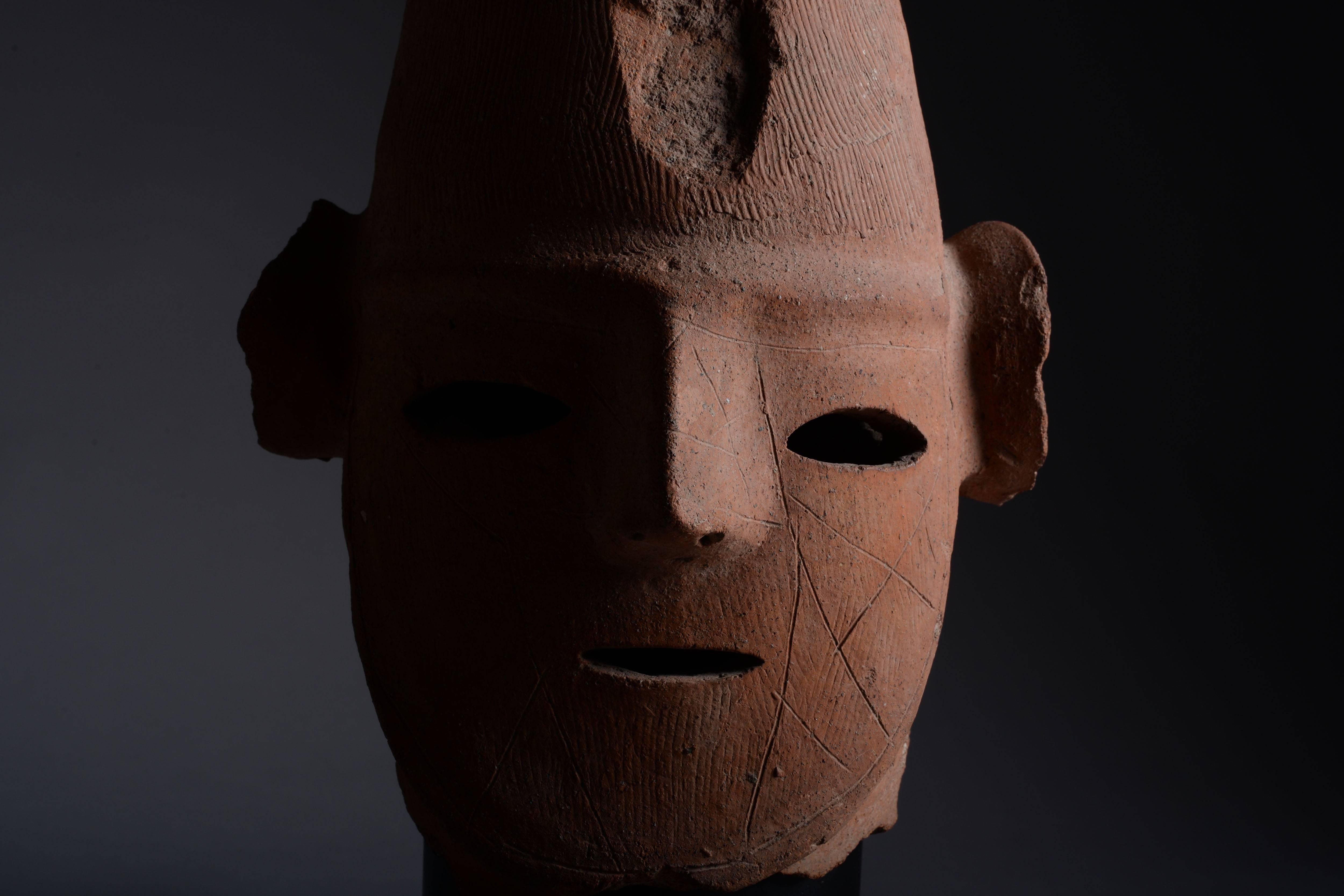 An exceptional example of Japanese Haniwa sculpture, dating to the Kofun (or Tumulus) Period, 4th-6th century AD.

The figure, probably depicting a shaman or shamaness, is shown with tall bifurcated headdress and large conical ears, the austere