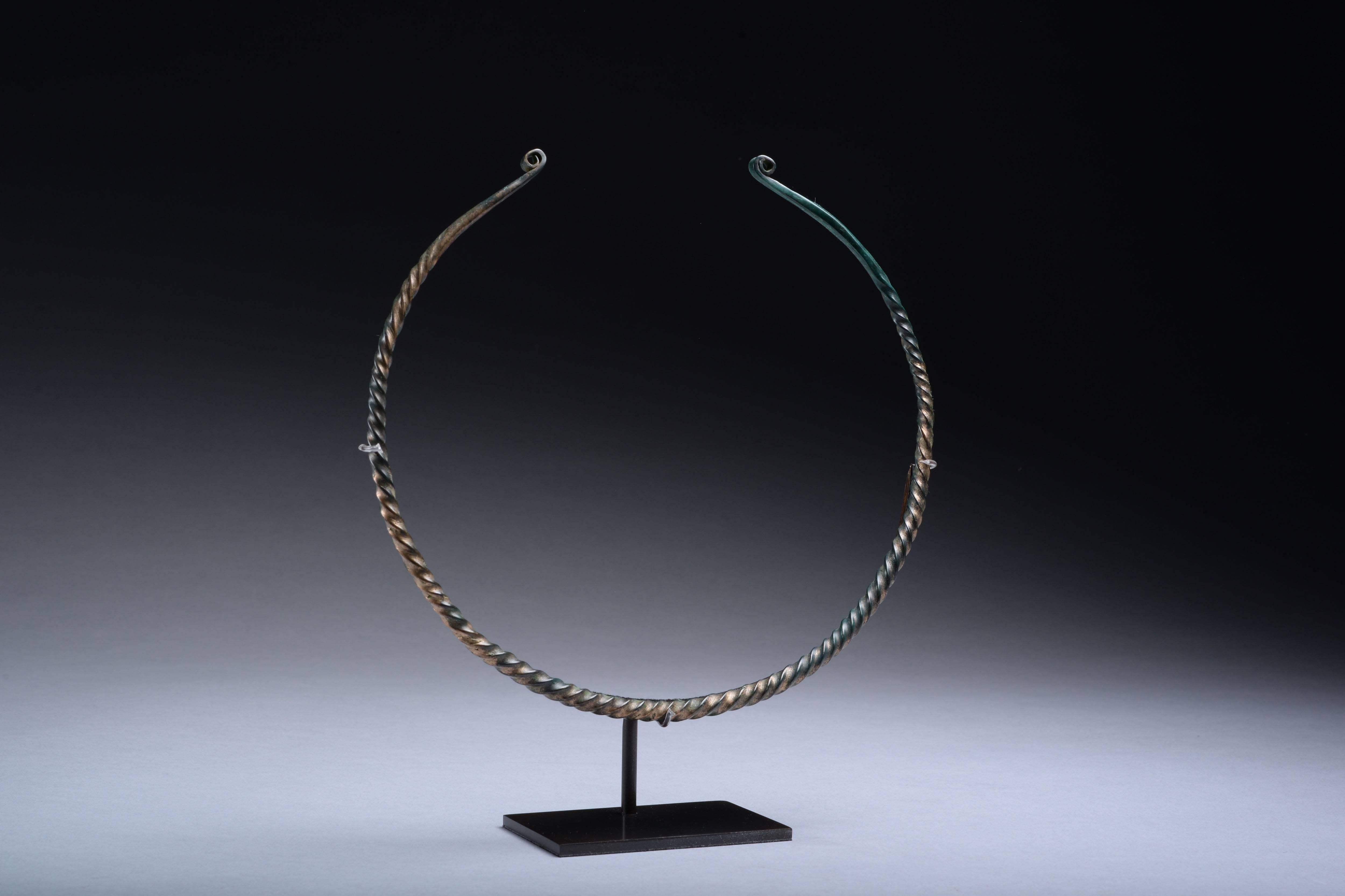 A striking European copper alloy neck torc, dating to the 9th-6th century BC.

Of elegant penannular form, twisted body and coiled terminals, displaying a marvellous green patina.

Torcs were status objects worn around the neck by the pre-Roman