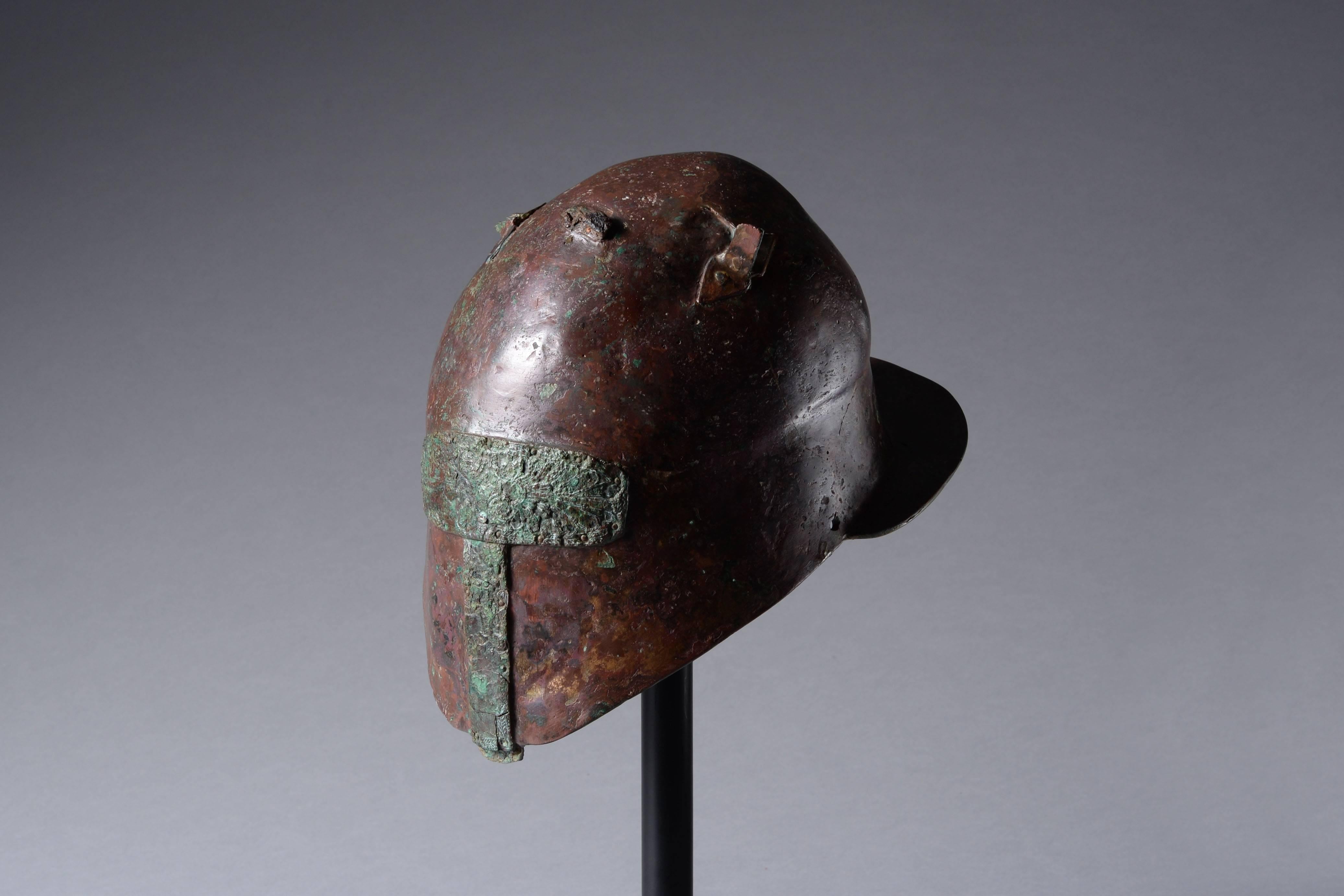 Un très rare casque grec ancien de type Apulo-Corinthien, endommagé et adapté pour la dédicace à l'époque antique, datant du 5ème siècle avant JC. 

Les casques de ce type sont originaires de l'actuelle Italie du Sud. Ils ont été martelés à partir