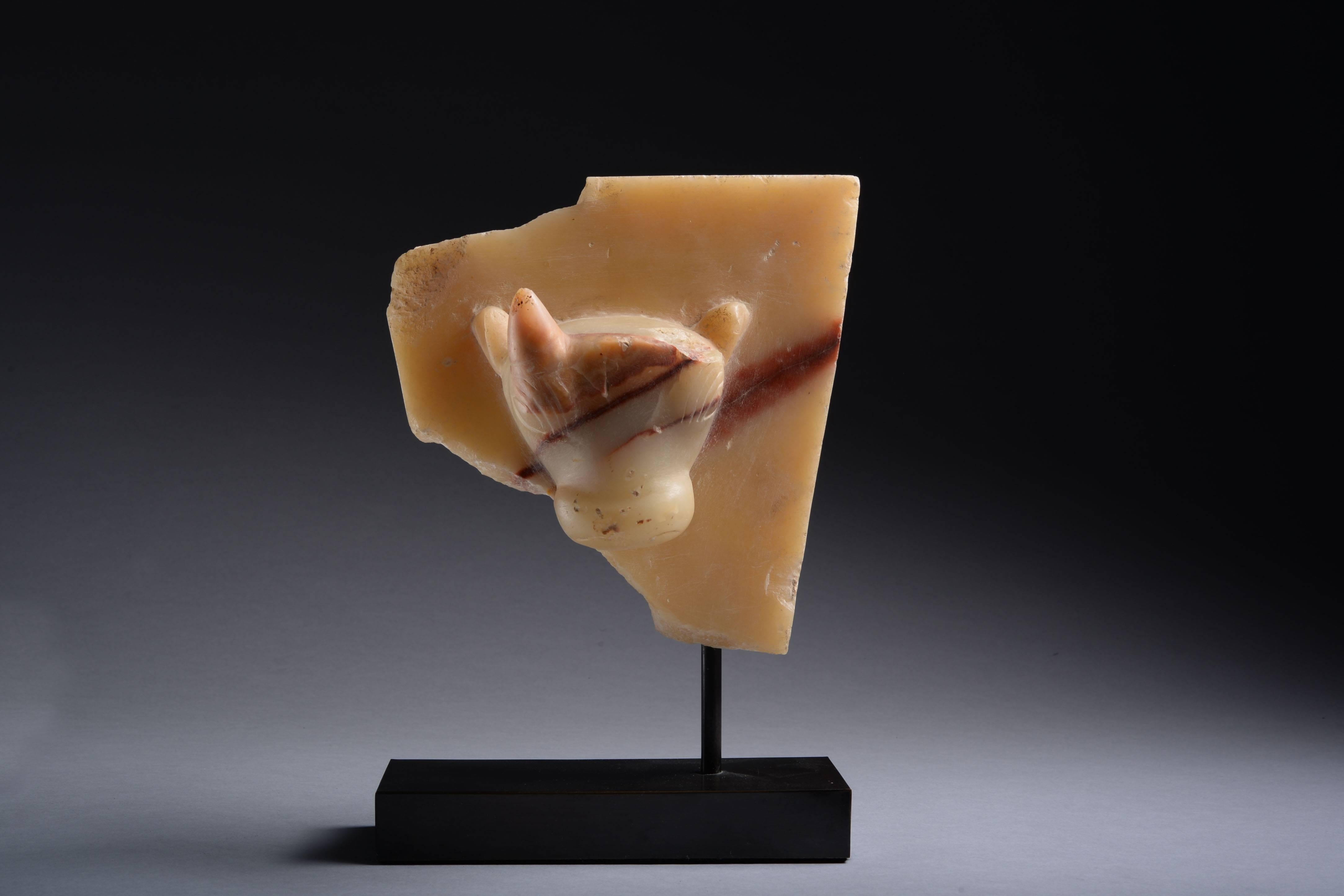 A South Arabian alabaster stele fragment, dating to the 1st century BC-1st century AD.

Carved from a block of red veined alabaster, the centre with a bull's head, in high relief. The creature is shown with conical horns and raised ears, the