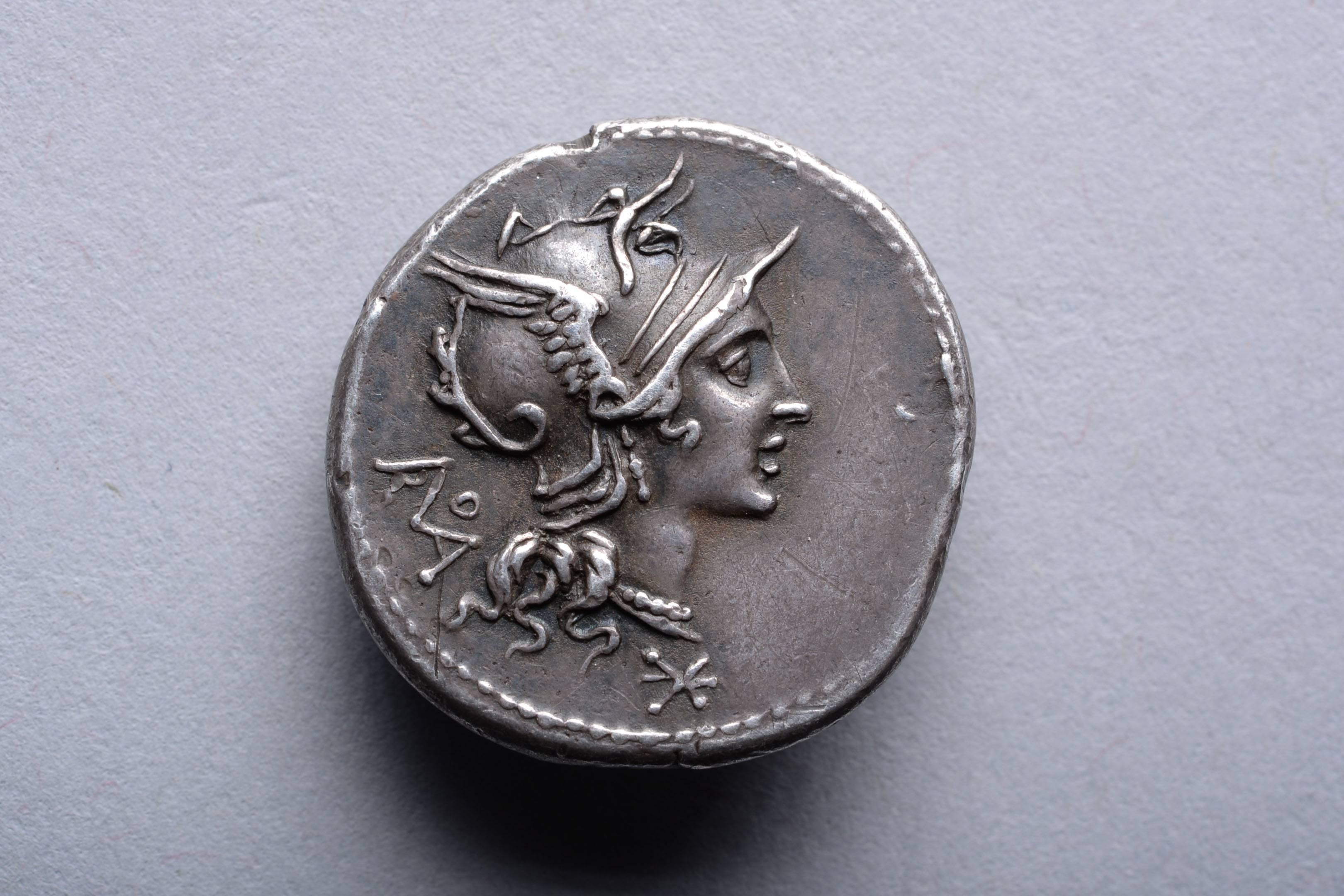 A Republican period silver denarius issued at the Rome mint, under T. Didius, in 113-112 BC.

The obverse with Roma, patron deity of Rome. The goddess wears a crested and winged helmet and beaded necklace, the locks of her hair flowing down her
