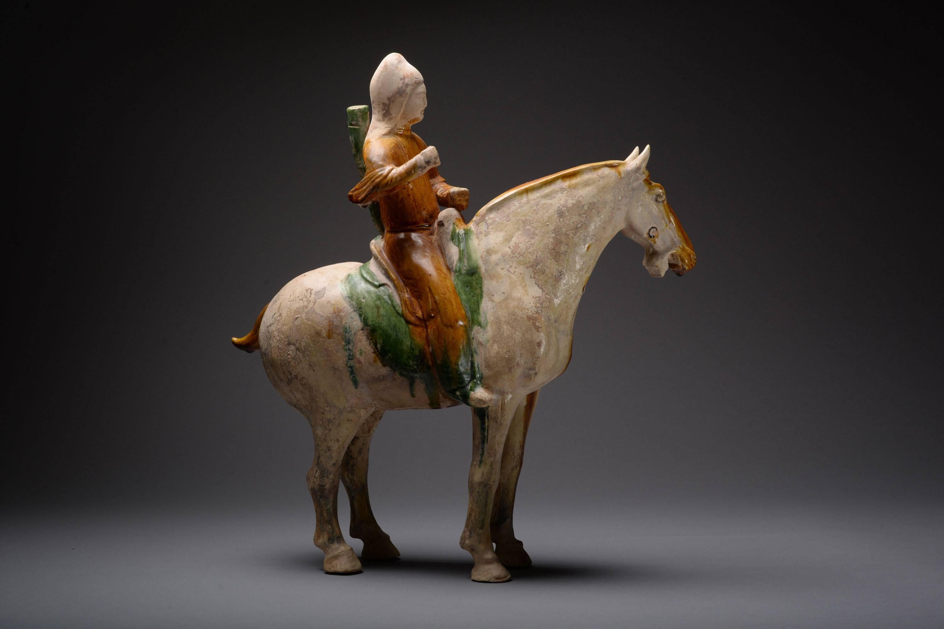 A magnificent ancient Chinese pottery figure of an Archer on horseback, dating to the Tang dynasty, approximately 618-907 AD.

The horse stands foursquare, head turned slightly to the left, mouth open. Its body with straw glaze, save for a deep