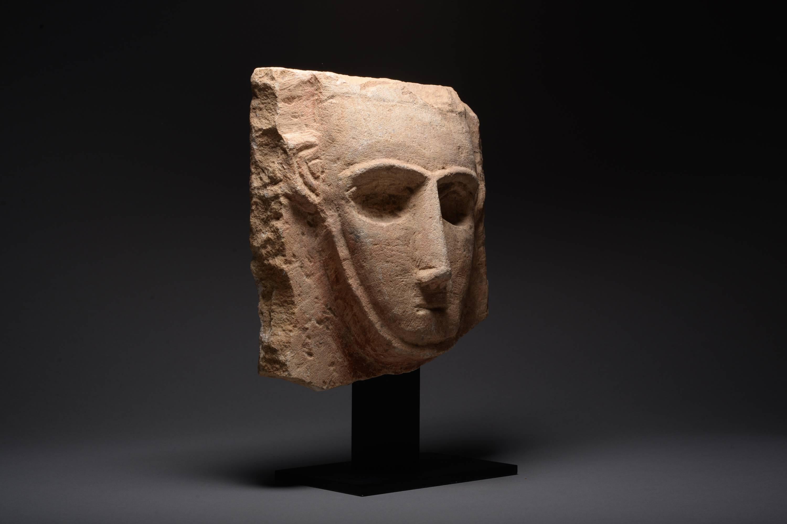 An ancient South Arabian limestone pillar stele, dating to the 3rd – 1st century BC.

The head sculpted in relief with robust features; prominent ridge, long nose, almond-shaped hollow eyes and a terse mouth. 

Cut off by great deserts to the