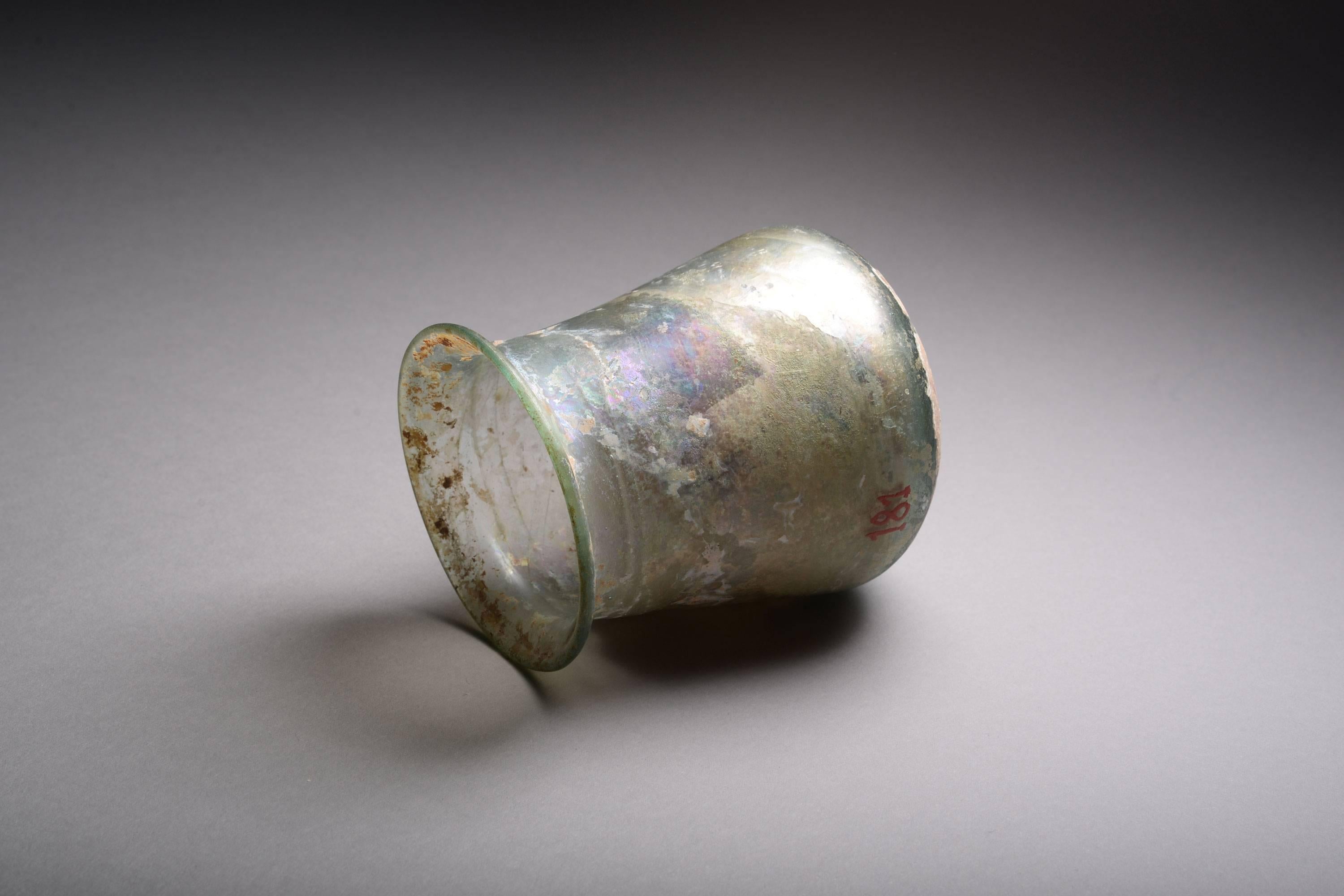 An ancient Roman glass beaker, dating to around 150 AD.

The green glass beaker with rainbow iridescence.  A beautiful glass shape, the beaker is a purely functional drinking vessel.  This example fits nicely into the hand, as it would have done